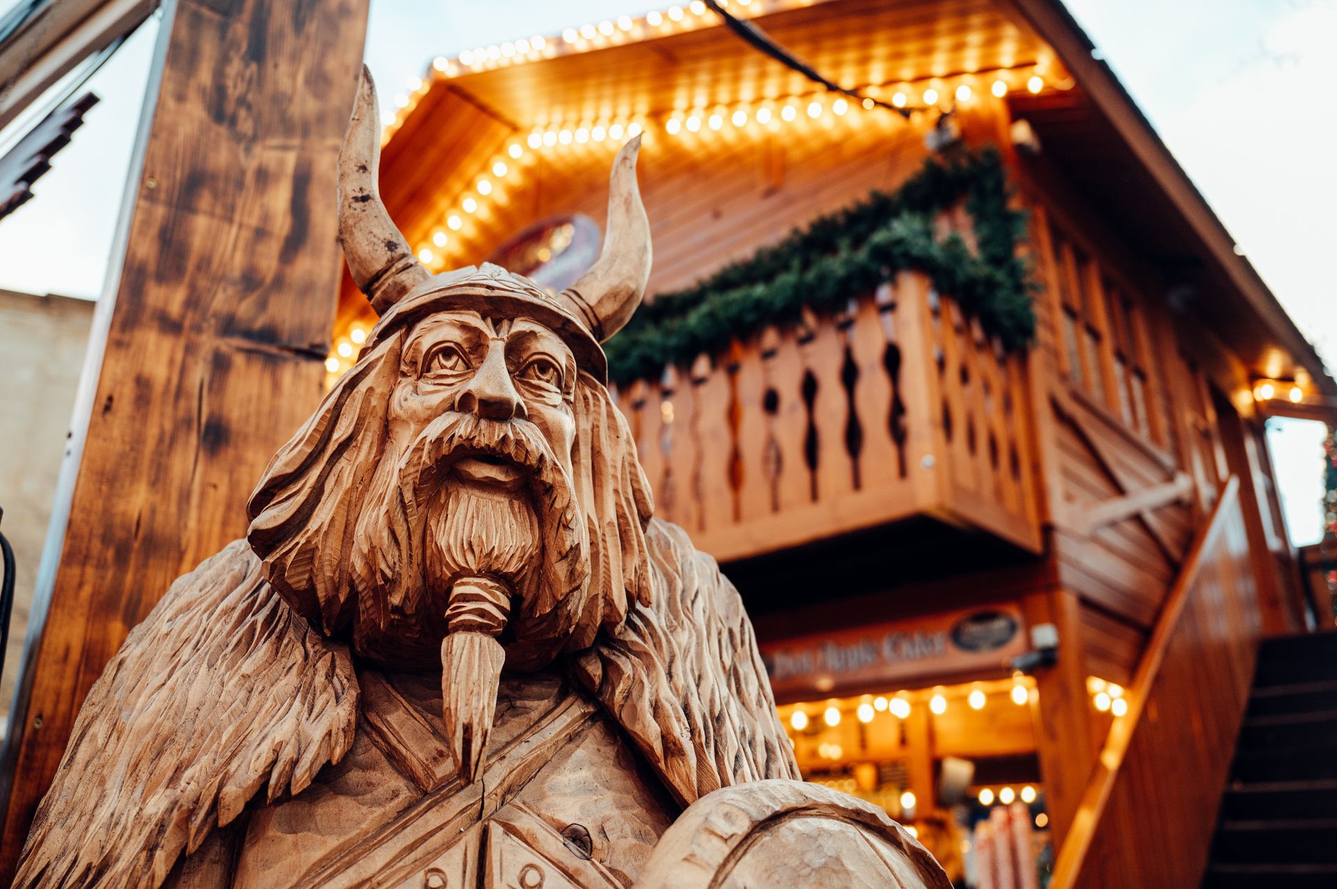 A statue of a viking standing in front of a wooden building