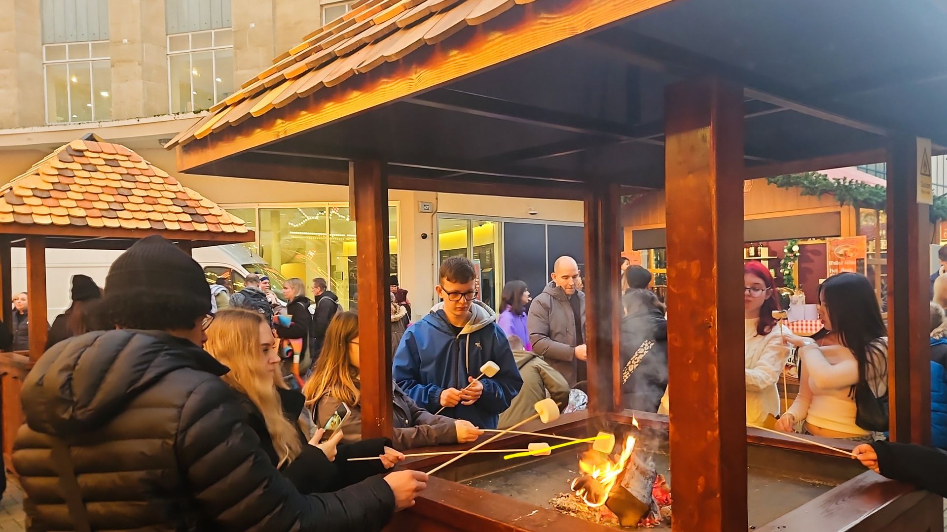 A group of people are gathered around a wooden structure cooking food