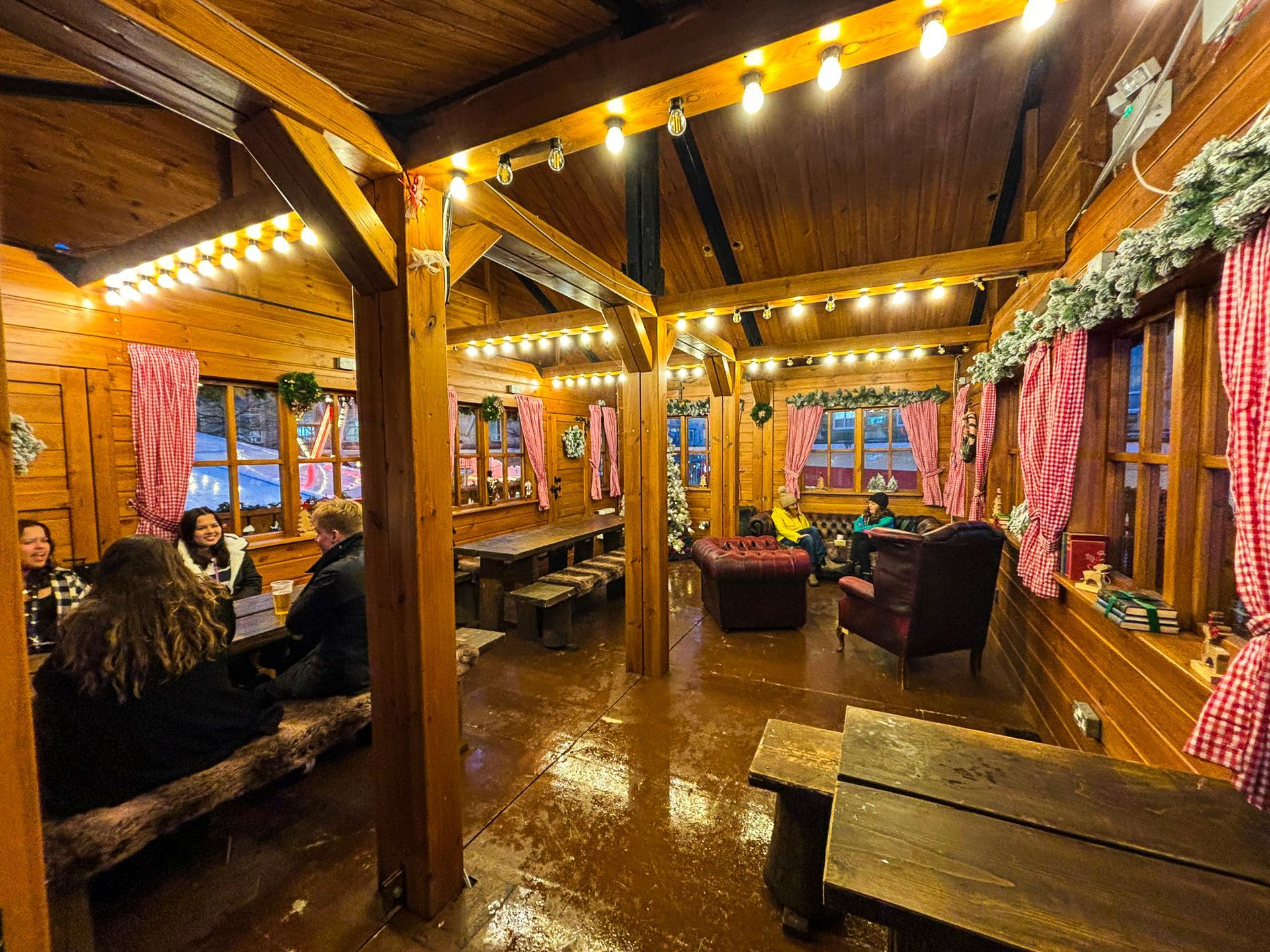 A group of people are sitting at tables in a wooden room
