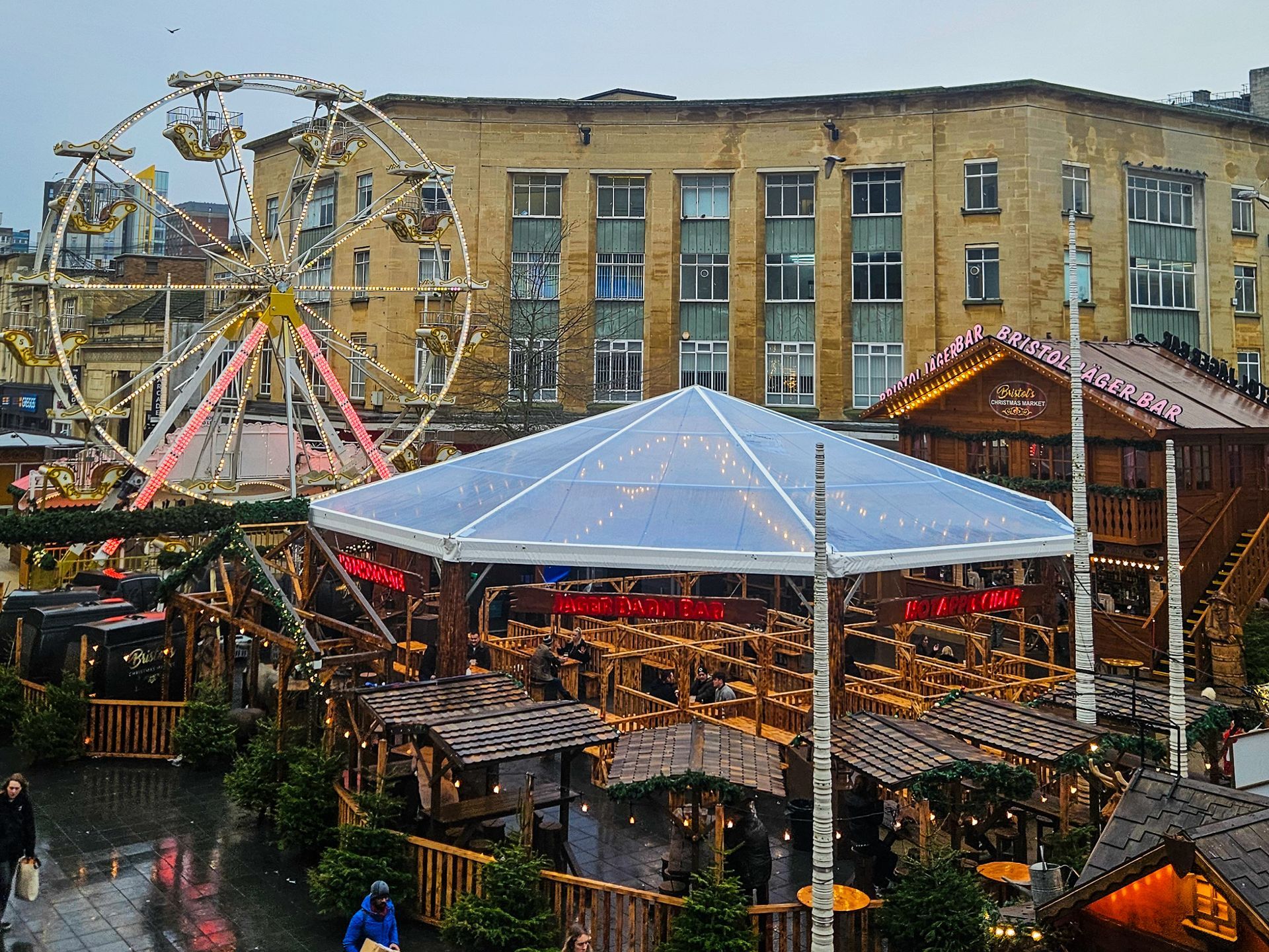 An aerial view of a christmas market with a ferris wheel in the background