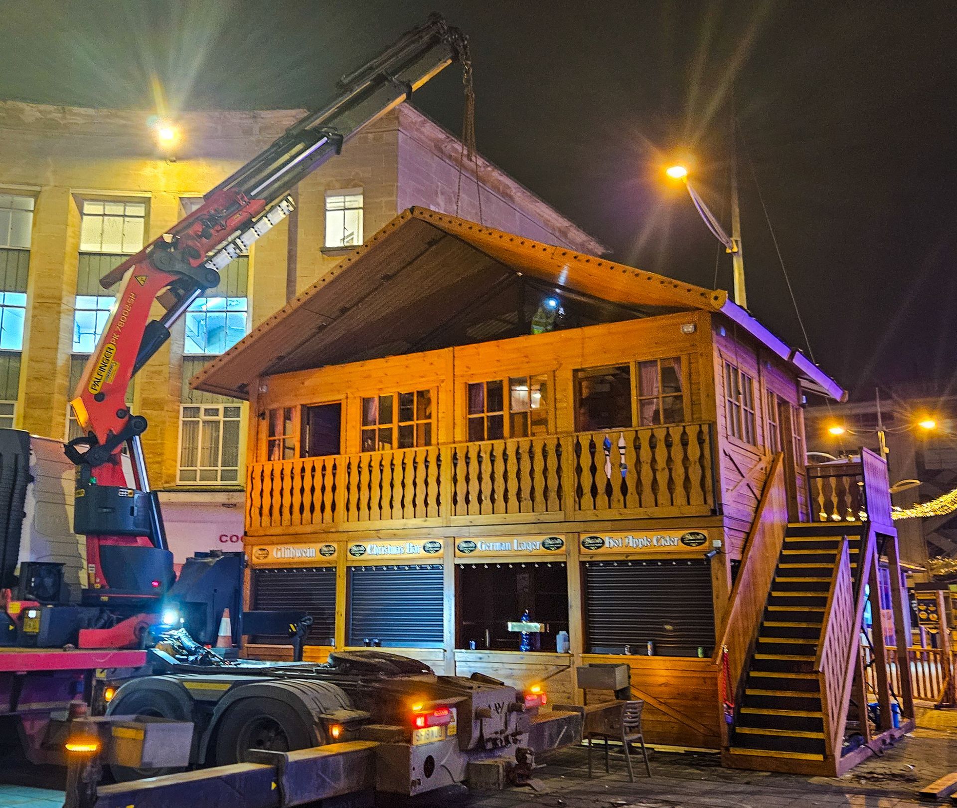 A crane is lifting a wooden house with stairs