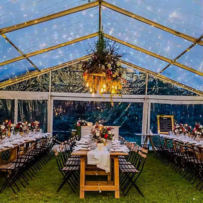 A long table and chairs under a clear tent.