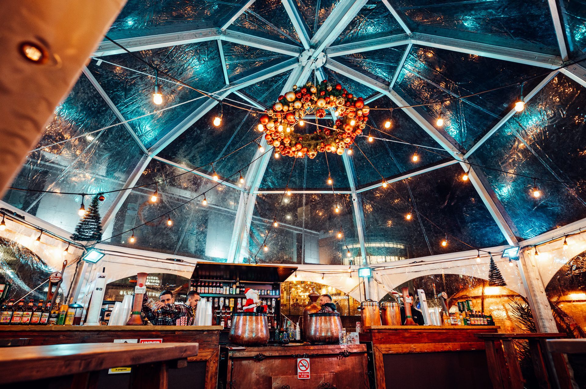 A clear dome with a christmas wreath hanging from the ceiling