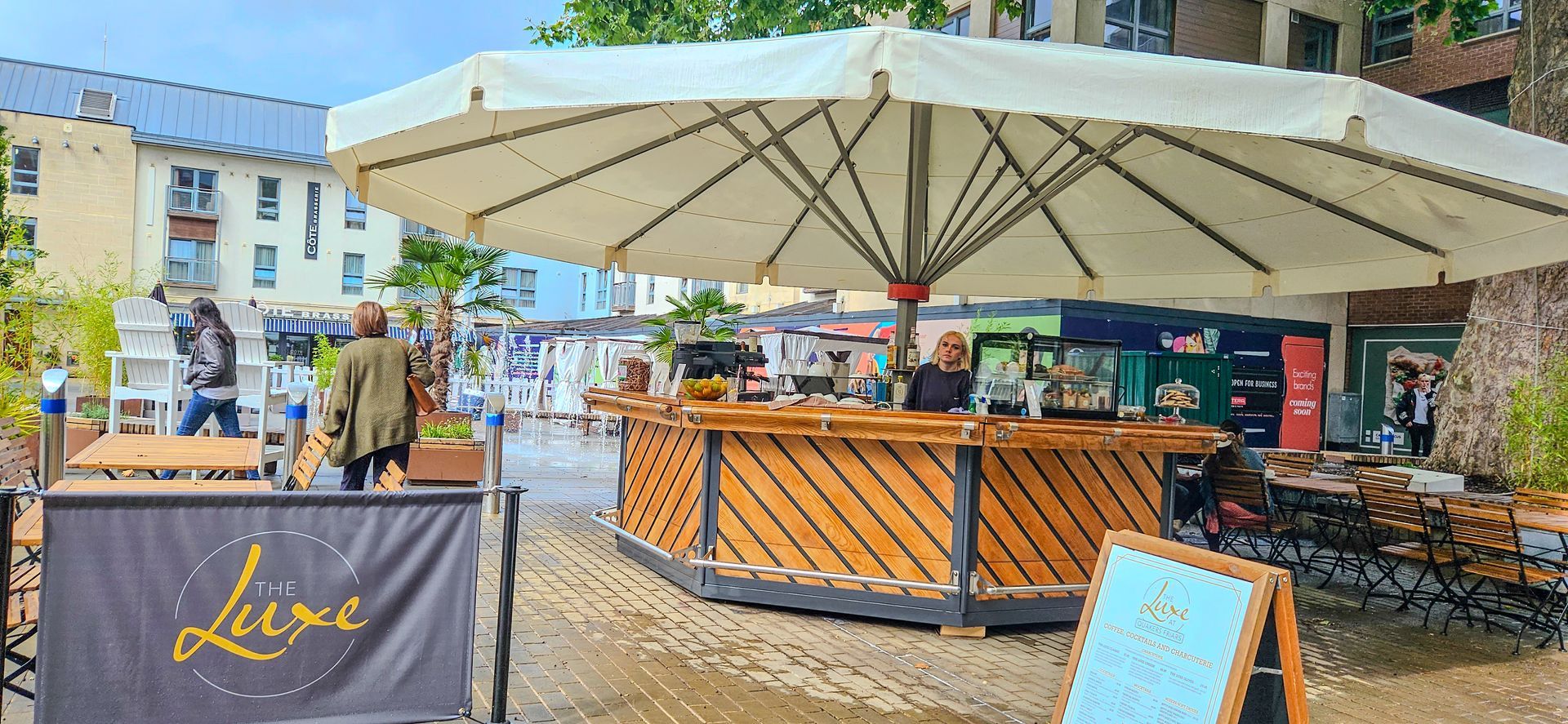 A large white umbrella is sitting in front of a restaurant