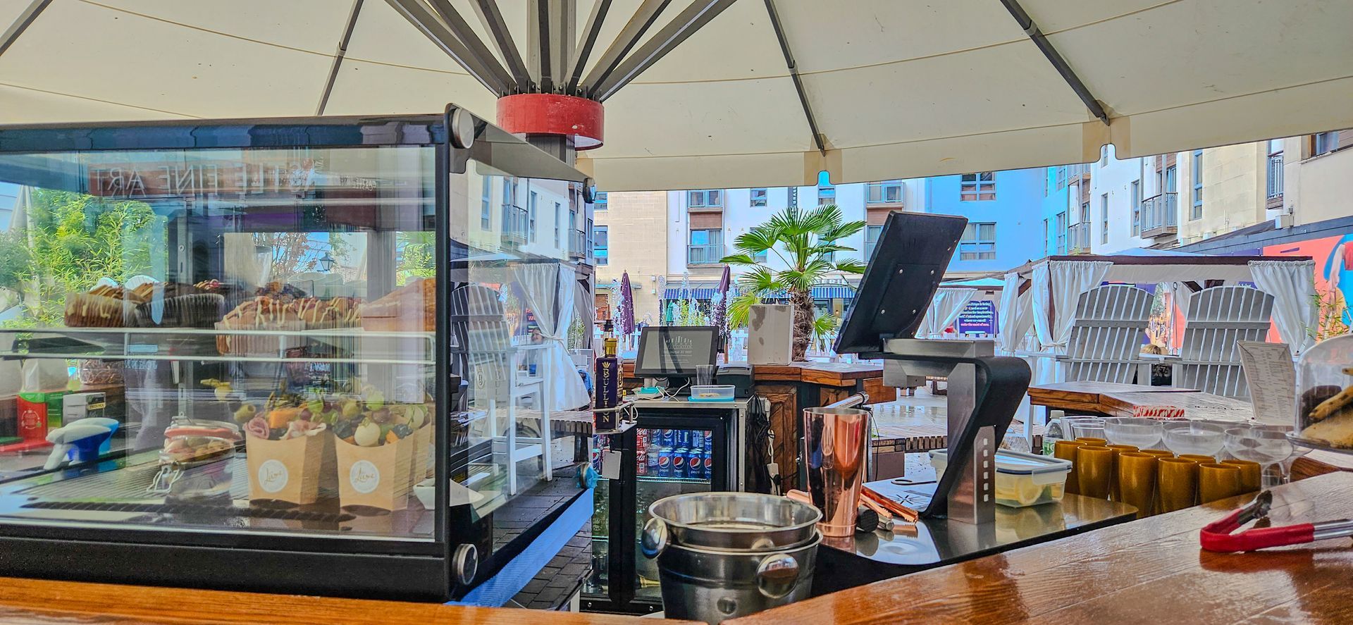 A restaurant with an umbrella and a display case of food