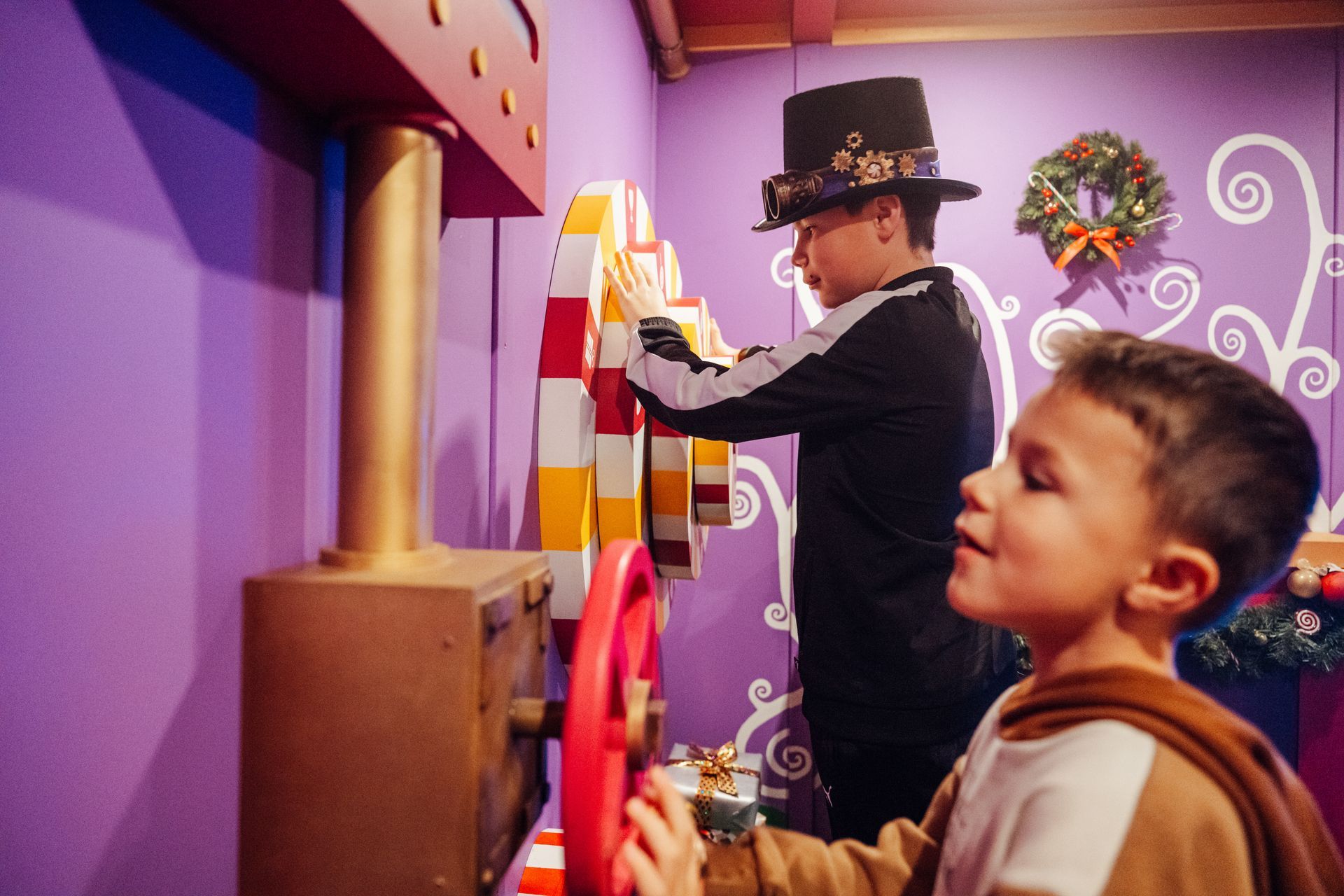A boy wearing a top hat is playing with a toy