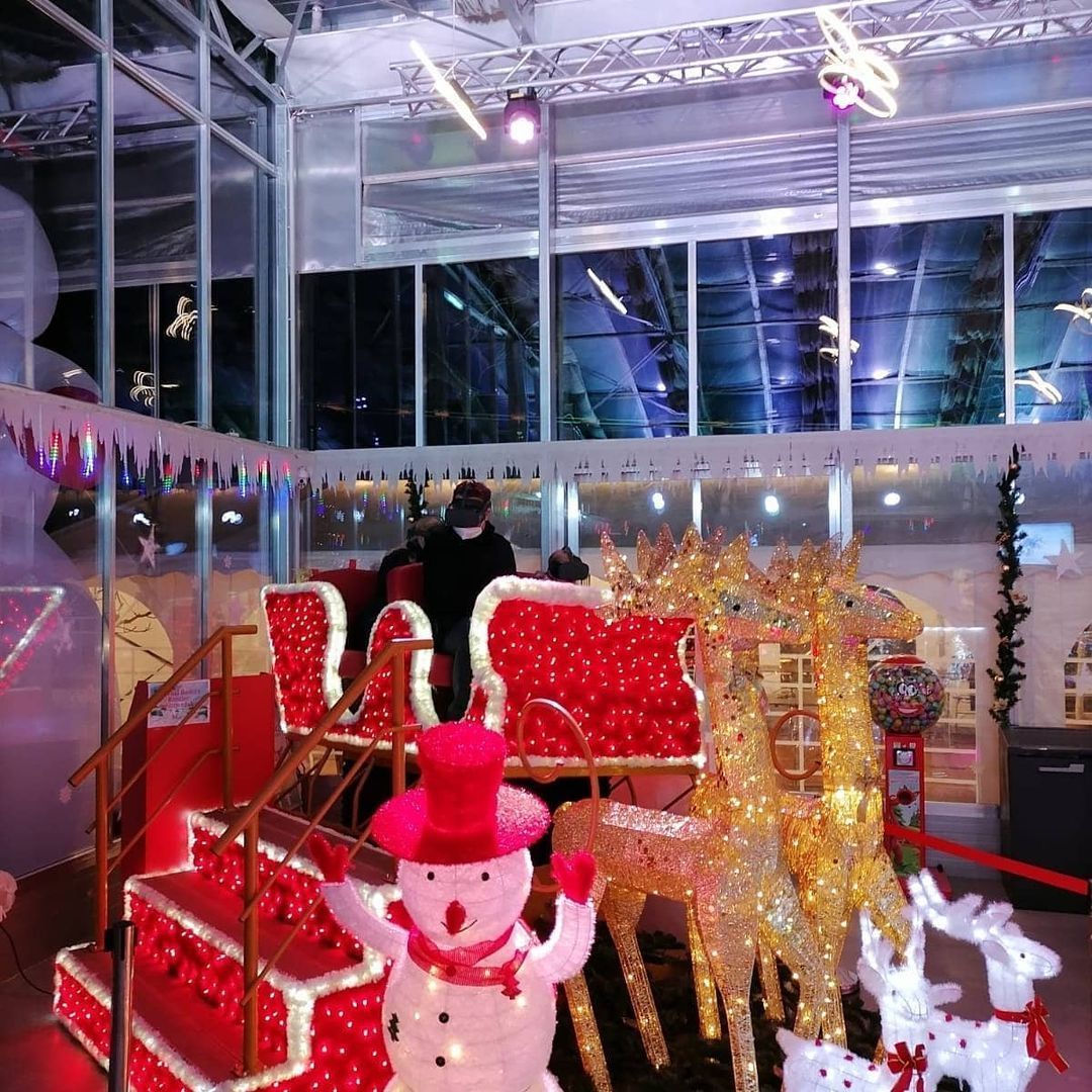 A snowman wearing a pink top hat is surrounded by christmas decorations