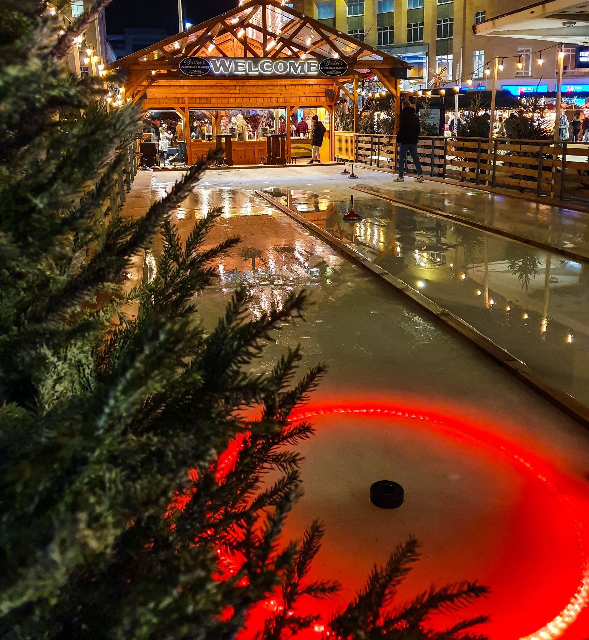 A christmas tree in front of a real ice curling rink.