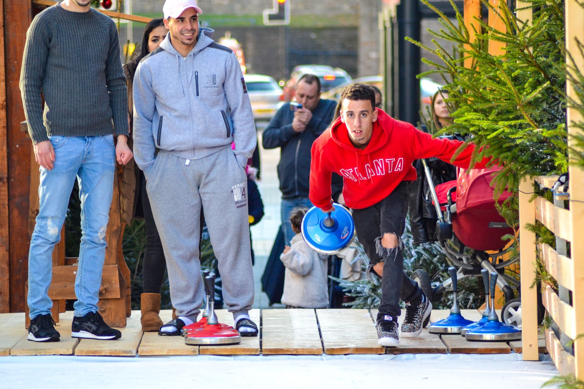 A man in a red sweatshirt playing ice curling.