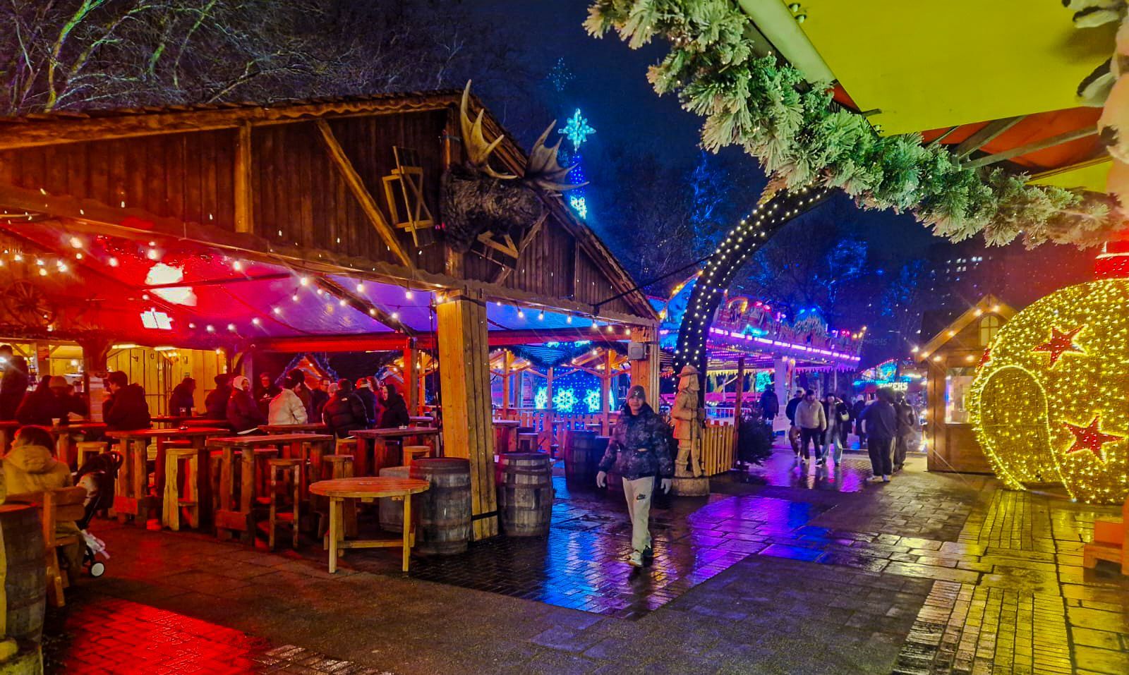 A crowd of people are gathered at a christmas market at night