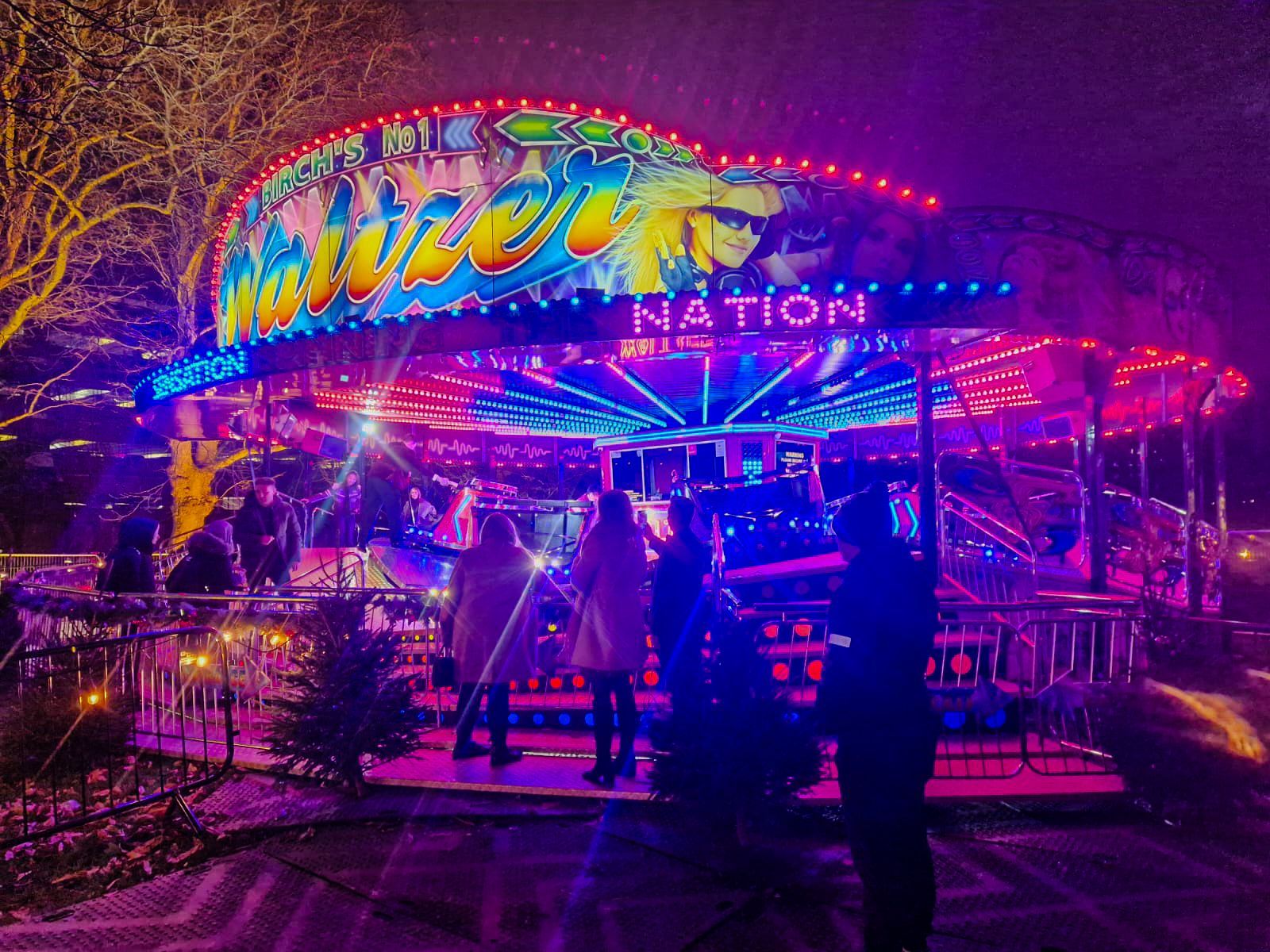 A group of people standing in front of a merry go round with the word nation on it