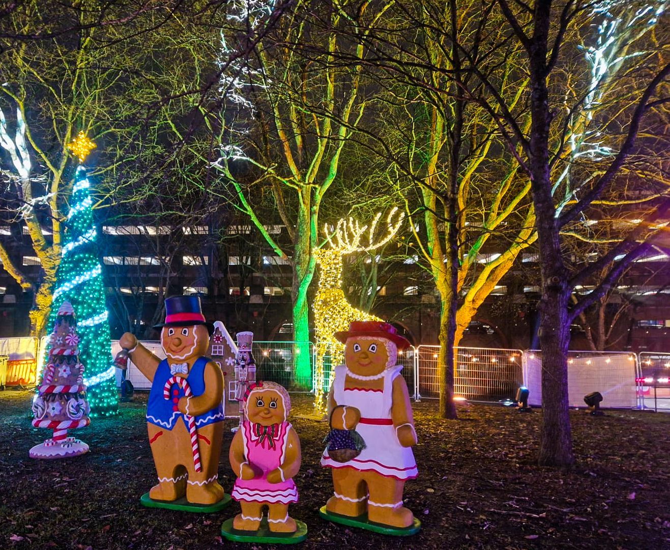A group of gingerbread people are standing in a park at night