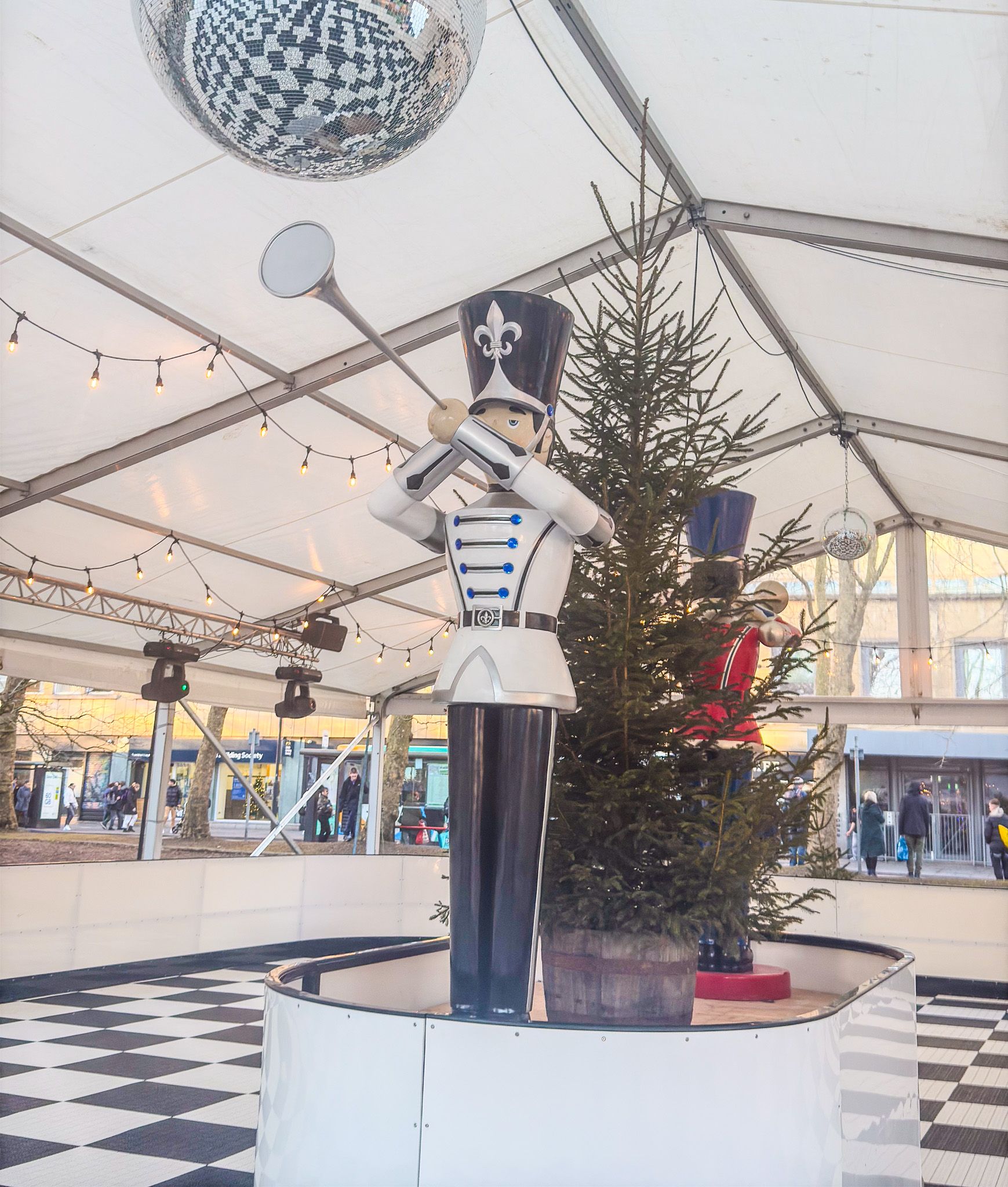 A statue of a nutcracker playing a trumpet next to a christmas tree