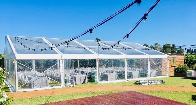 A large clear tent is sitting on top of a lush green field.