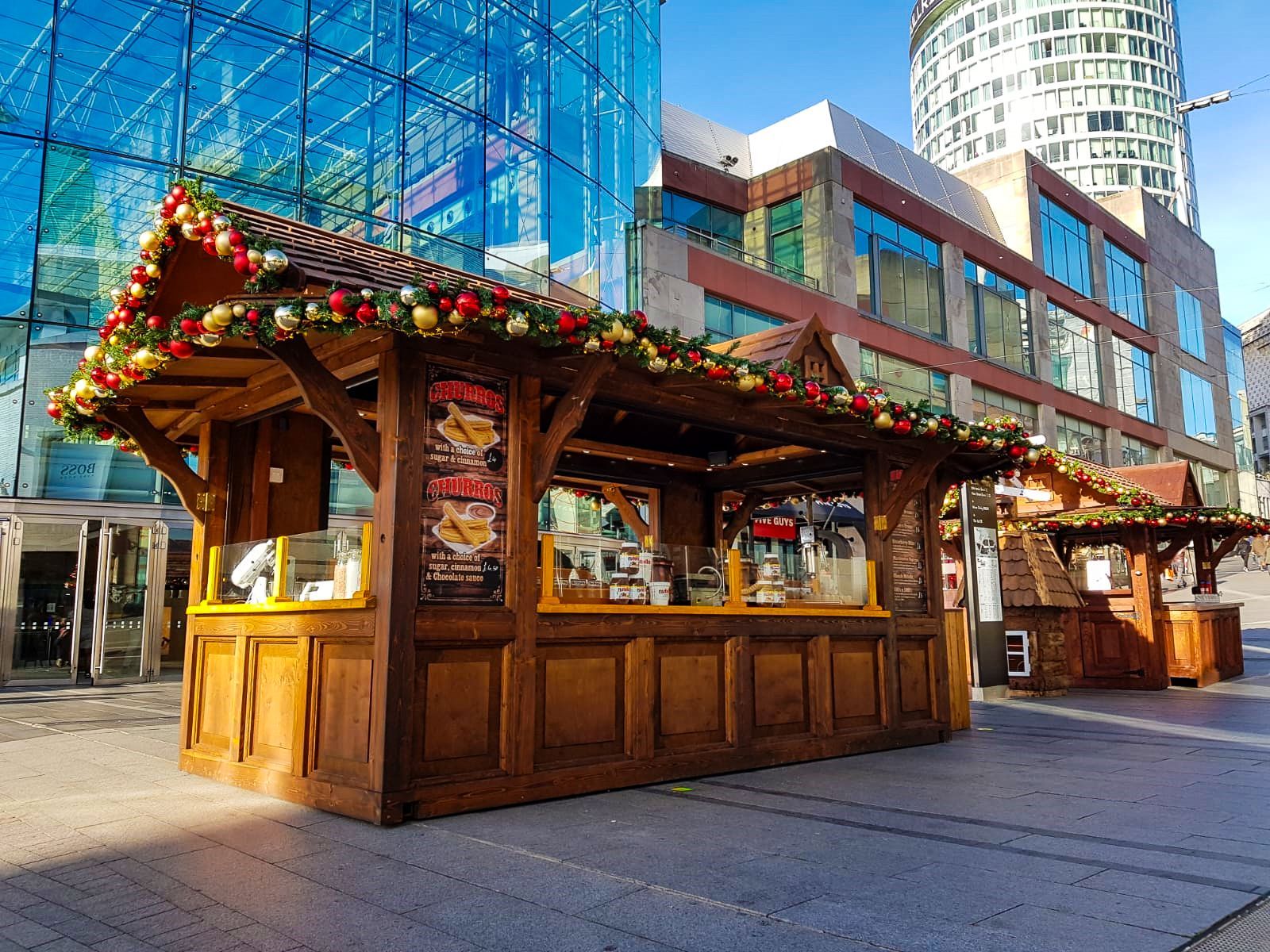 A wooden kiosk is decorated with christmas decorations in front of a building