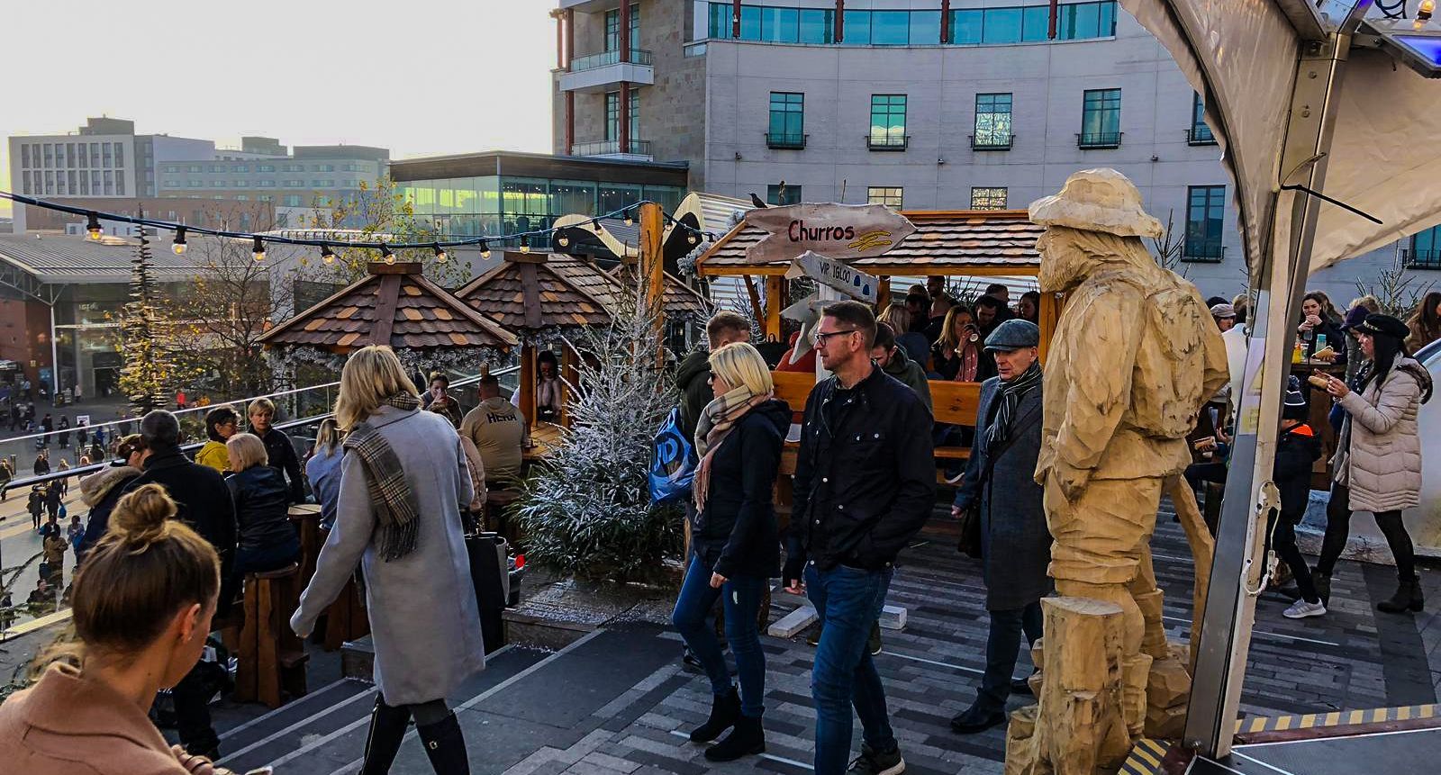 A crowd of people are gathered around a statue of a man in a hat