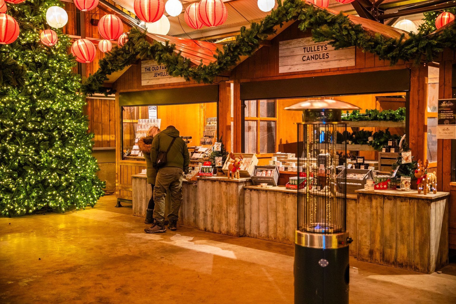 A man stands at a counter in front of a christmas tree