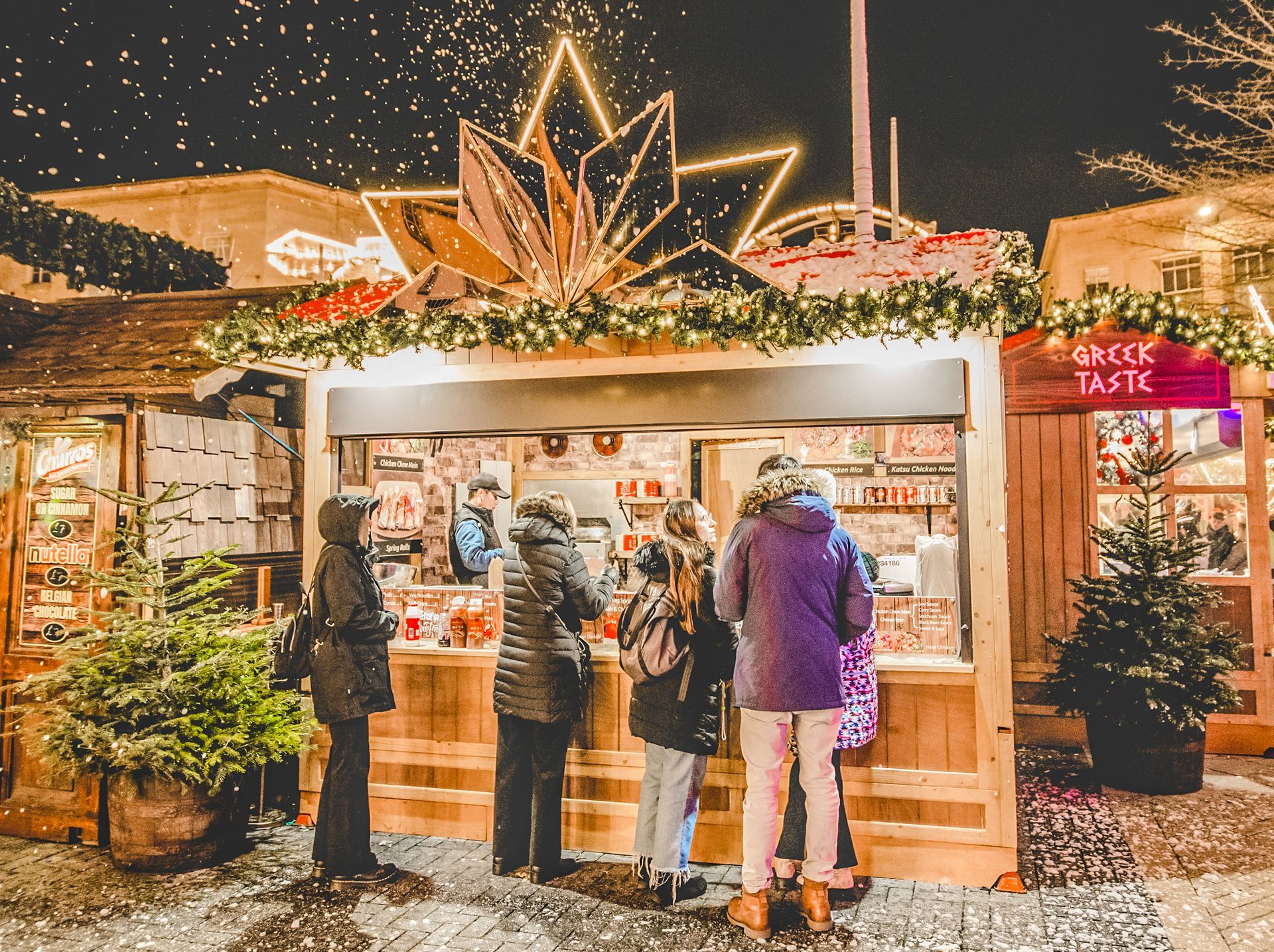 People standing in front of a booth that says greek taste
