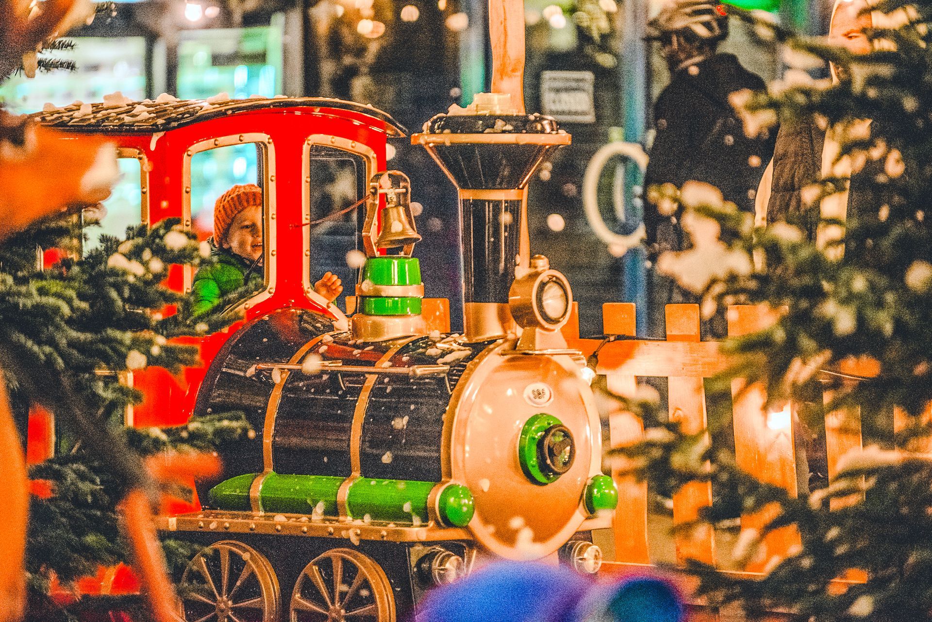 A toy train is sitting in front of a christmas tree