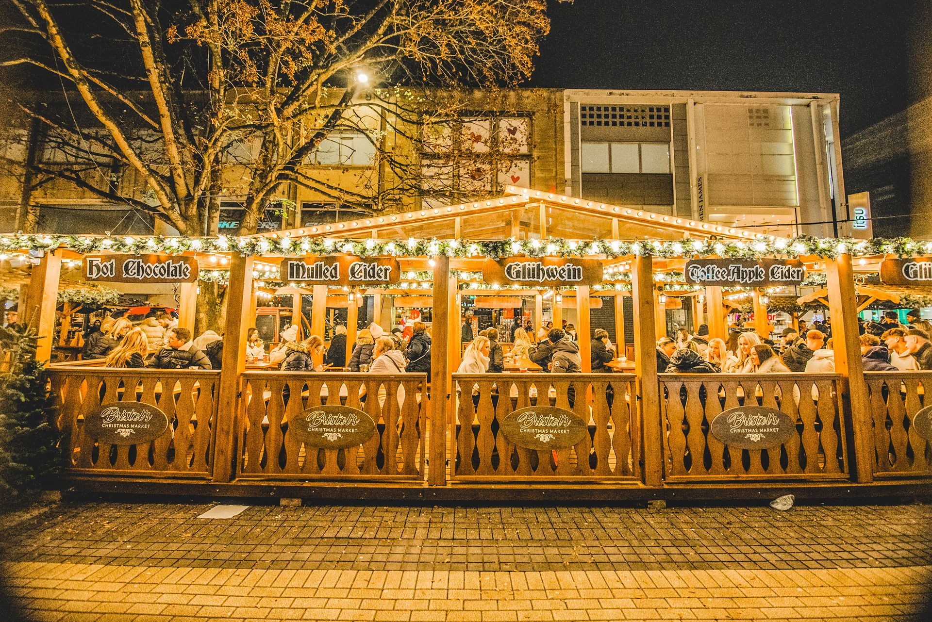 A wooden fence surrounds a christmas market at night