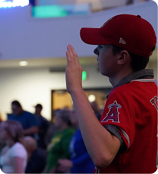 Baseball fan in a red Angels jersey and cap cheering at an indoor event