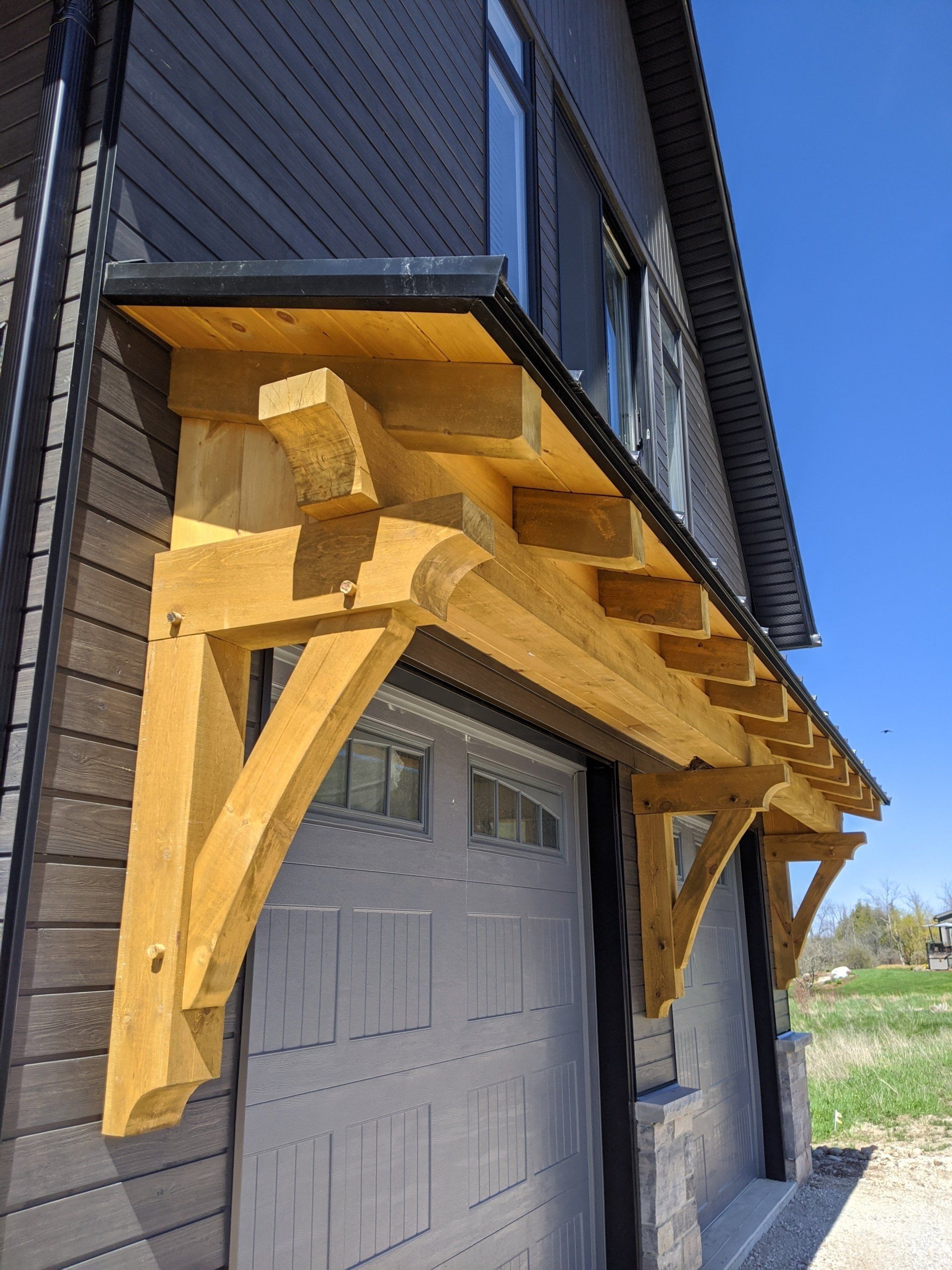 A wooden canopy over a garage door on the side of a building.