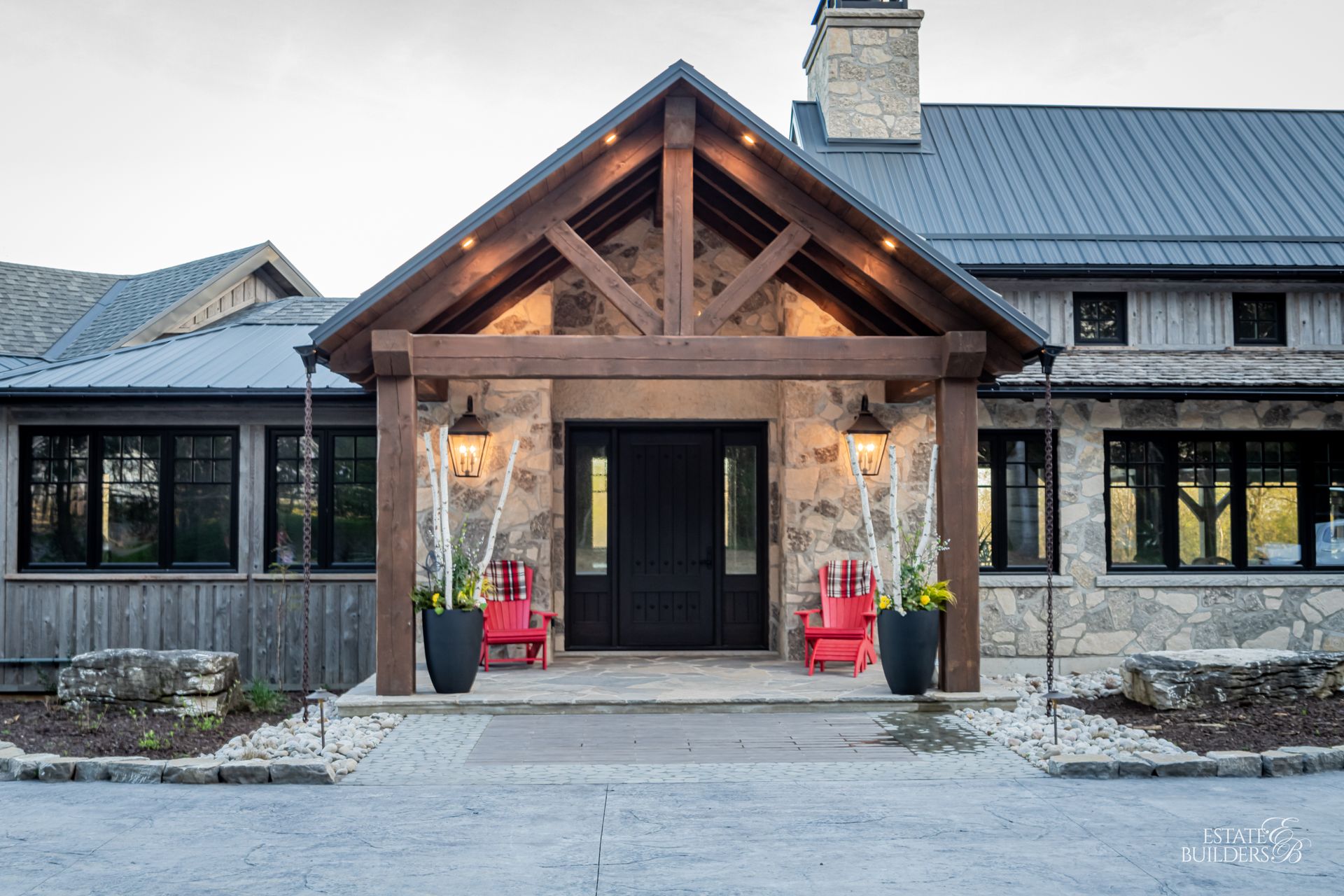 A large house with a timber frame porch and red chairs in front of it