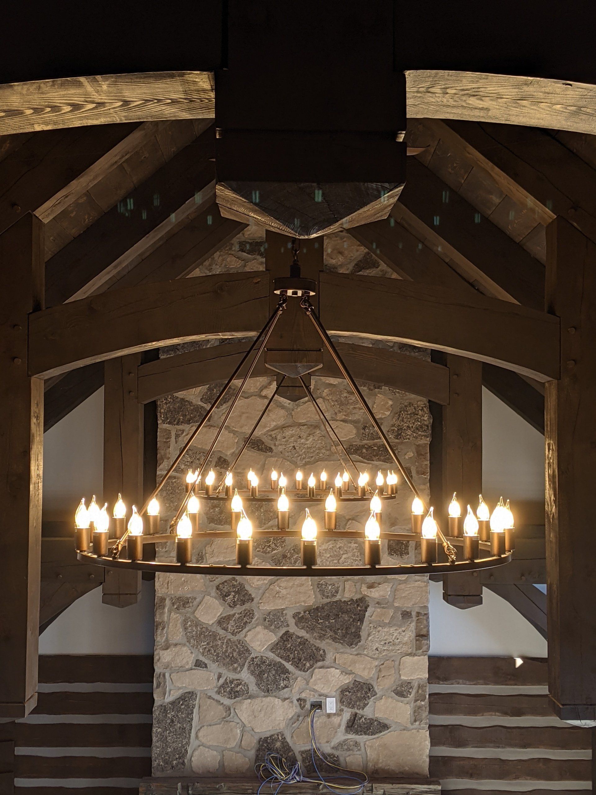 A large chandelier is hanging over a stone fireplace