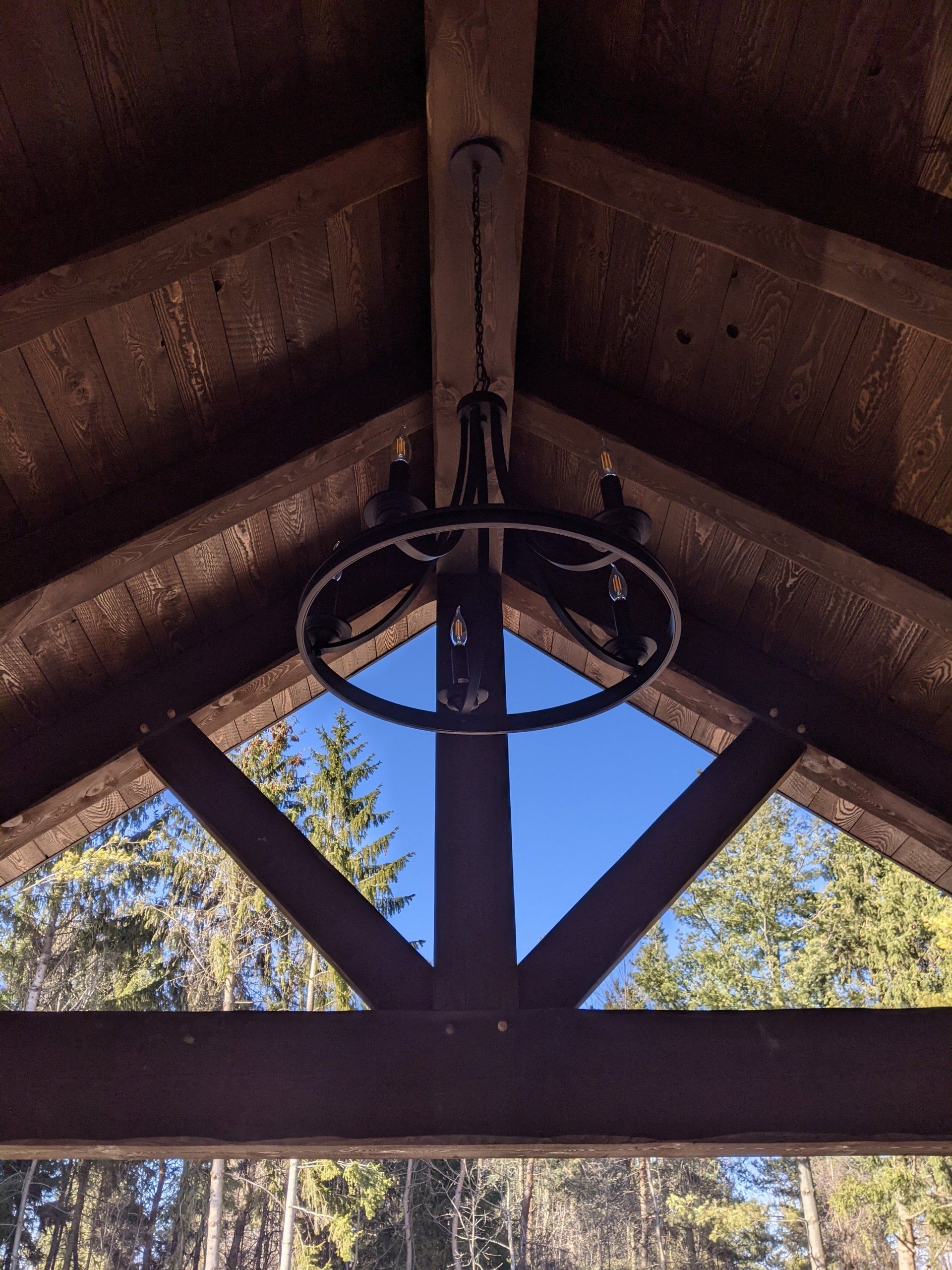 A chandelier is hanging from the ceiling of a wooden timber frame structure.