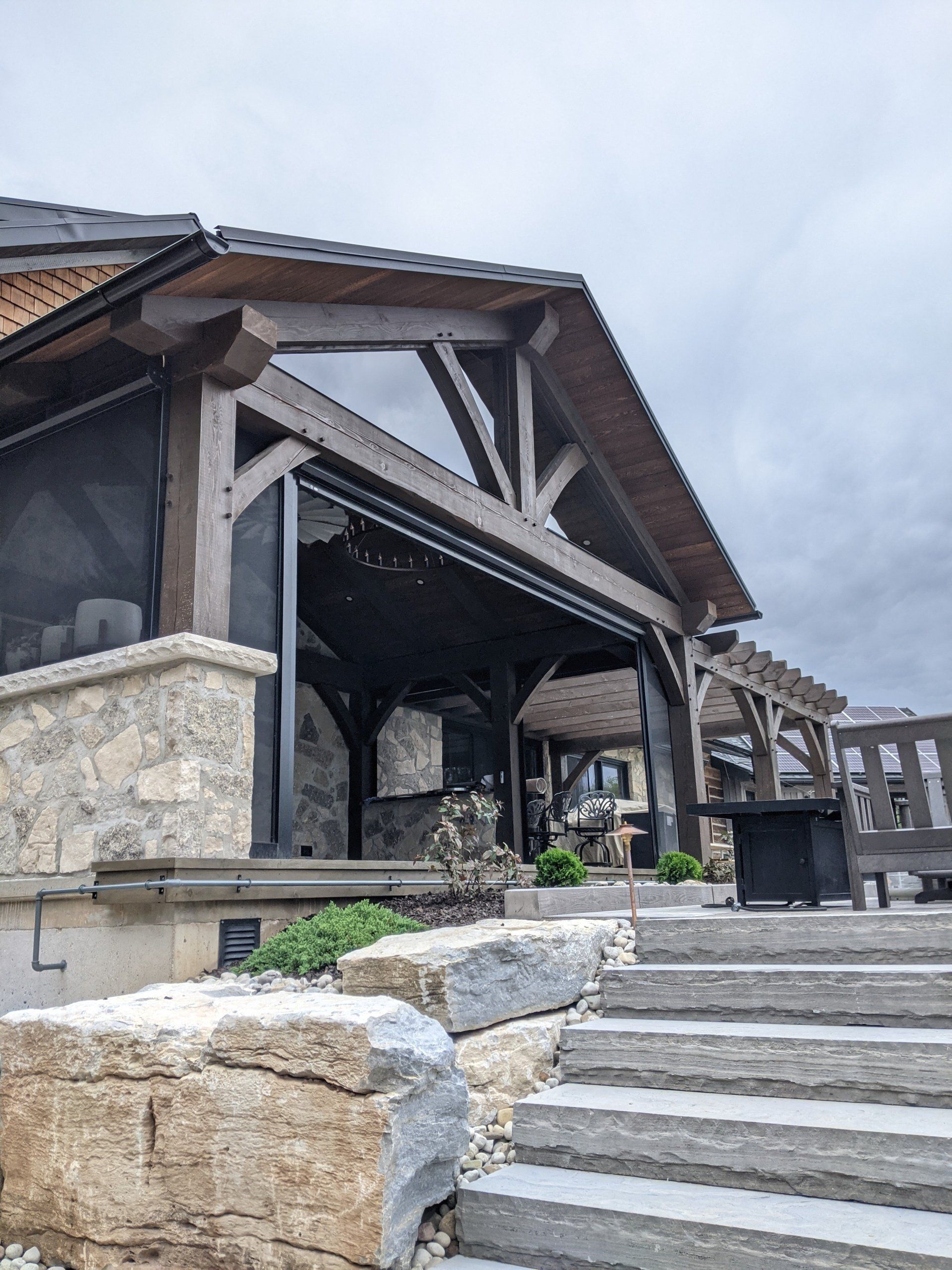 A house with stairs leading up to it and a screened in timber frame porch.