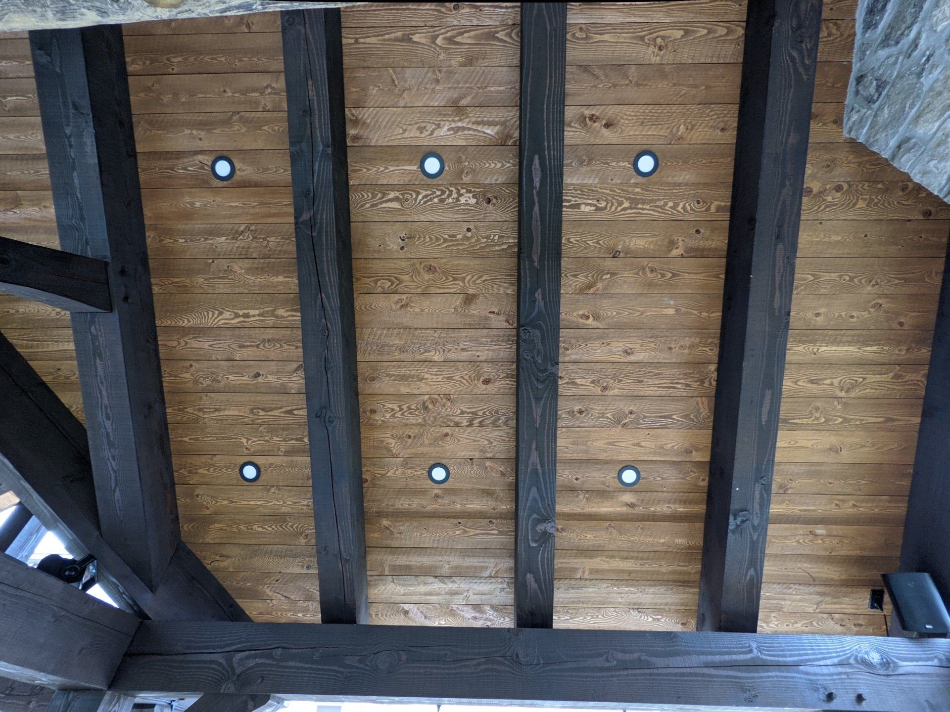 A wooden timber frame ceiling with black beams and lights