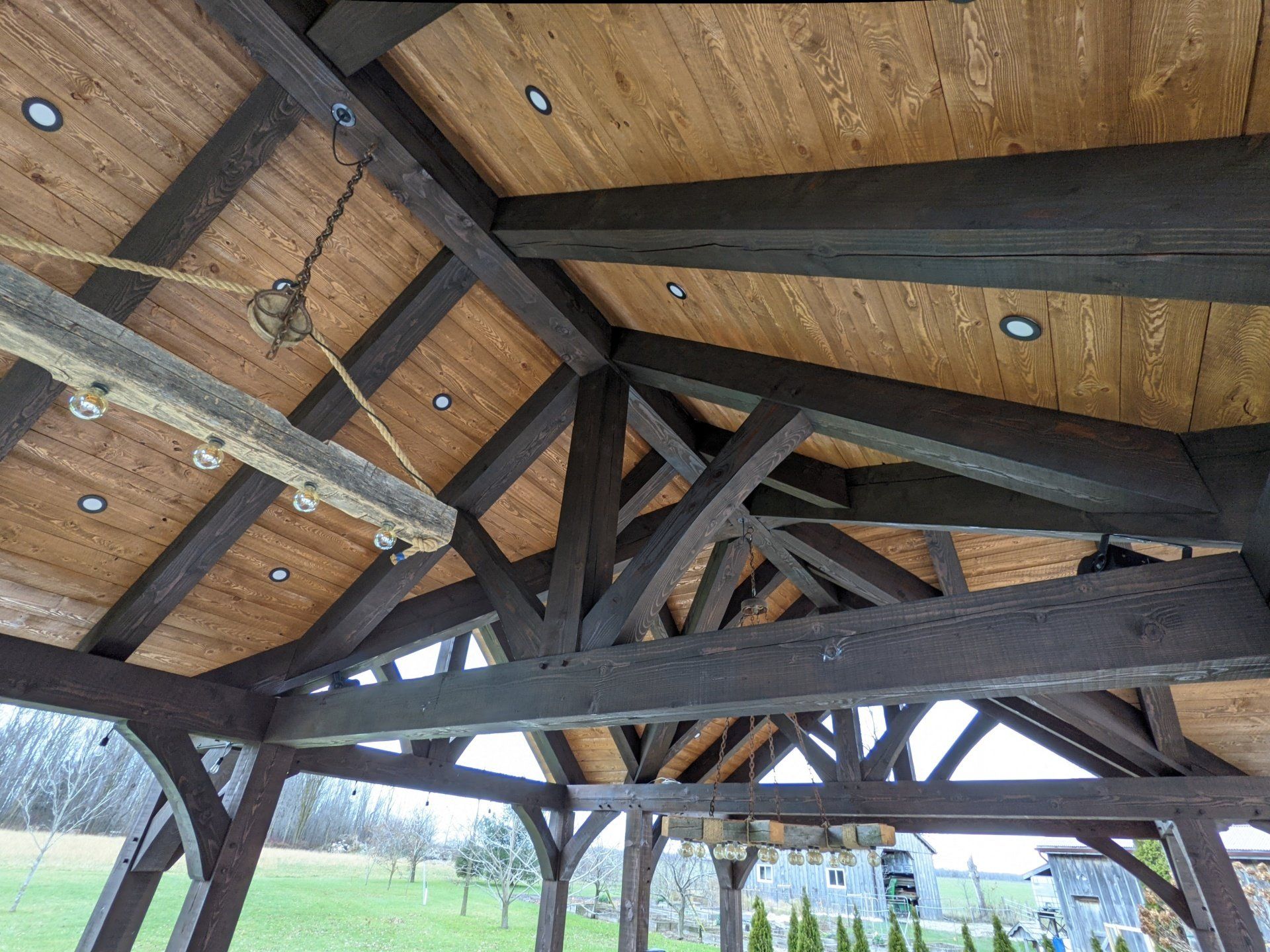 The ceiling of a wooden timber frame structure with a chandelier hanging from it.