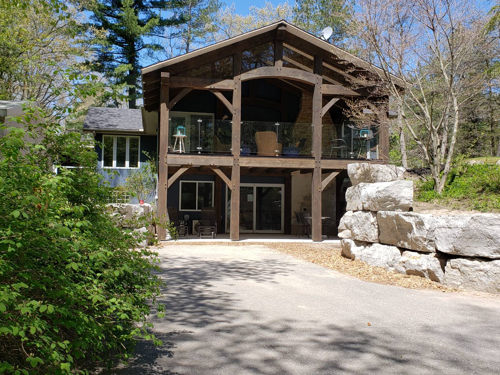 A large wooden house is surrounded by trees and rocks.