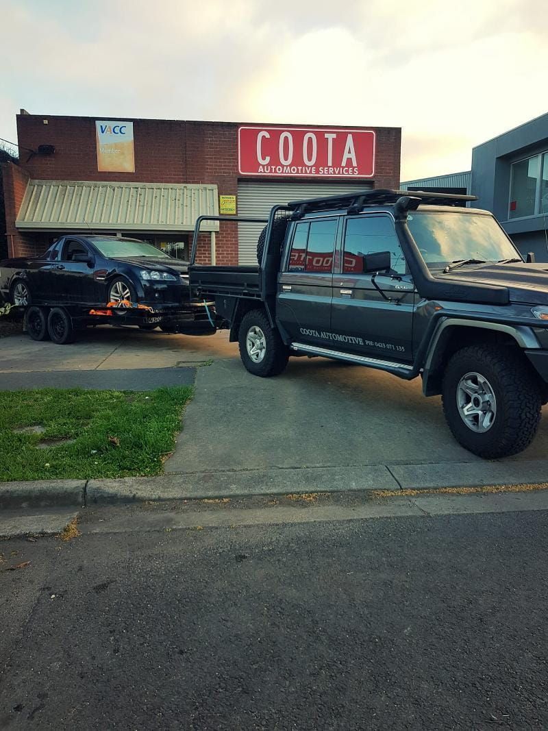 Dark Gray Truck Towing a Trailer With a Black Car — COOTA Automotive Services in Ballarat East, VIC