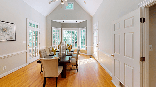 Formal dining room with wood floors, a long table, and window seats.