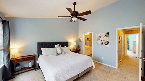 Bedroom with a bed, nightstands, light blue walls, and a ceiling fan.