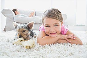 Little girl lying on rug with yorkshire terrier smiling at camera - Wireless Dog Fence in Jackson Hole, WY