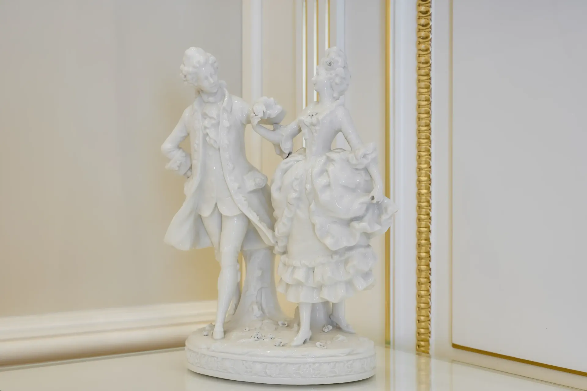 A white statue of a man and woman standing next to each other on a table.