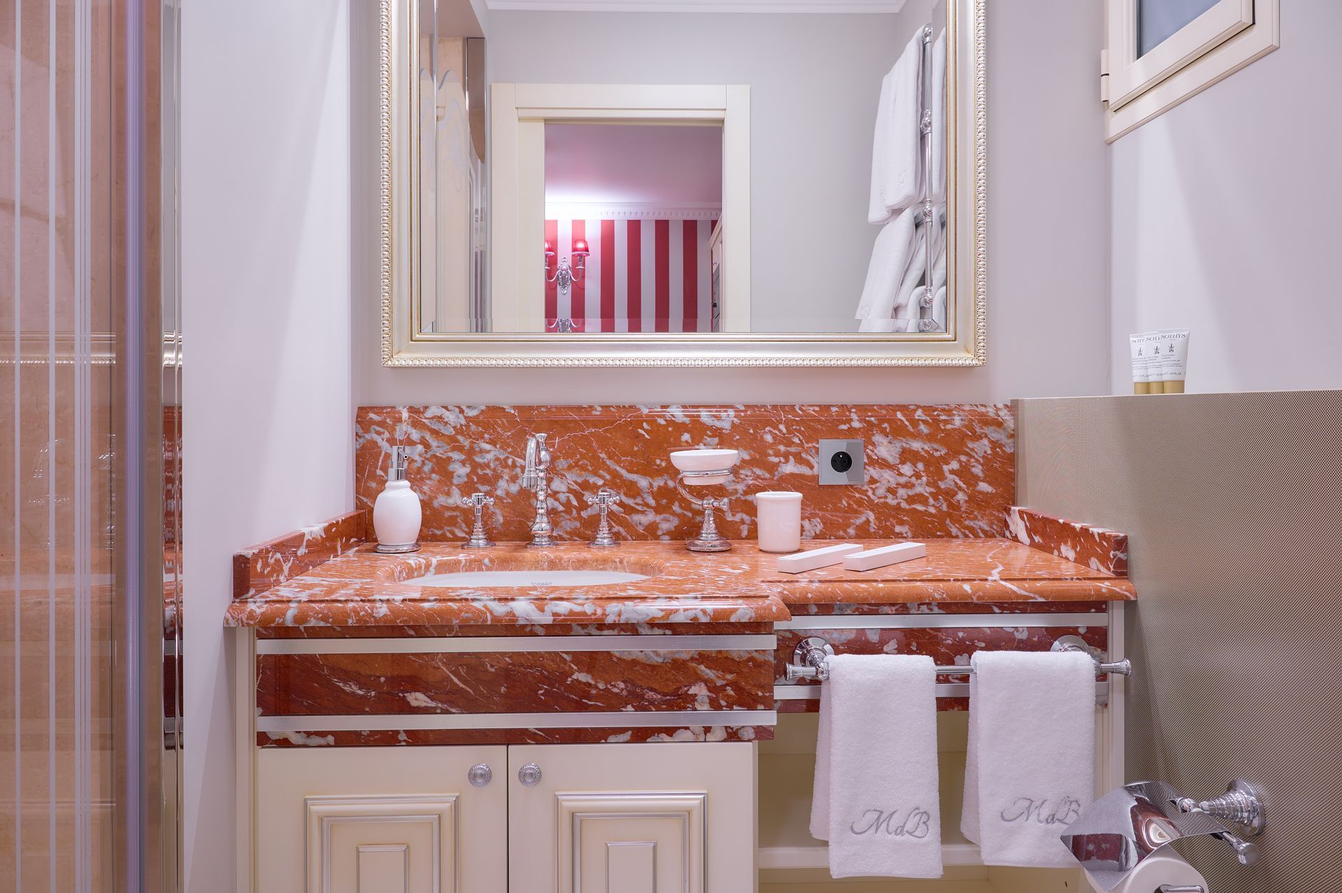 A bathroom with a sink , mirror , and towels.