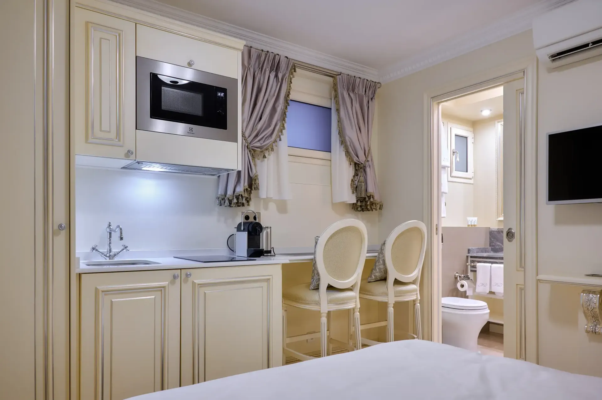A hotel room with a bed , chairs , a microwave and a television.