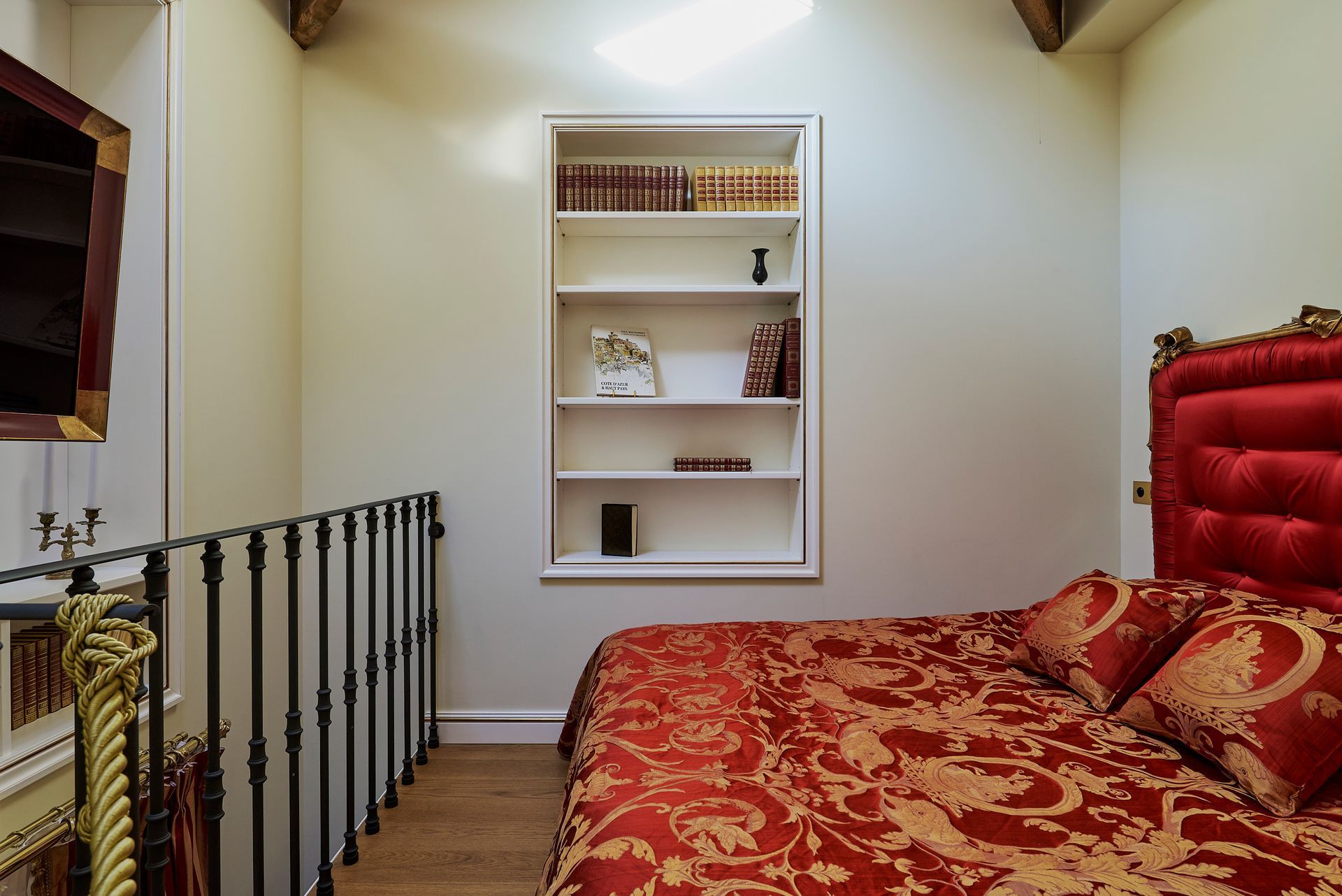 A bed with a red headboard and white sheets in a bedroom.