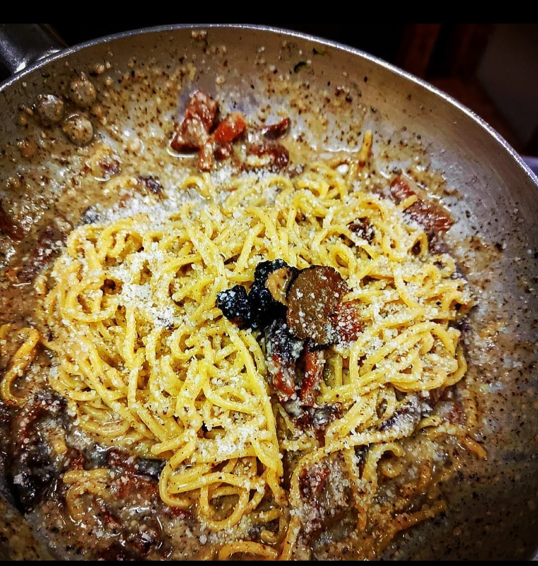 Piatto di pasta in padella, con funghi, formaggio e salsa.