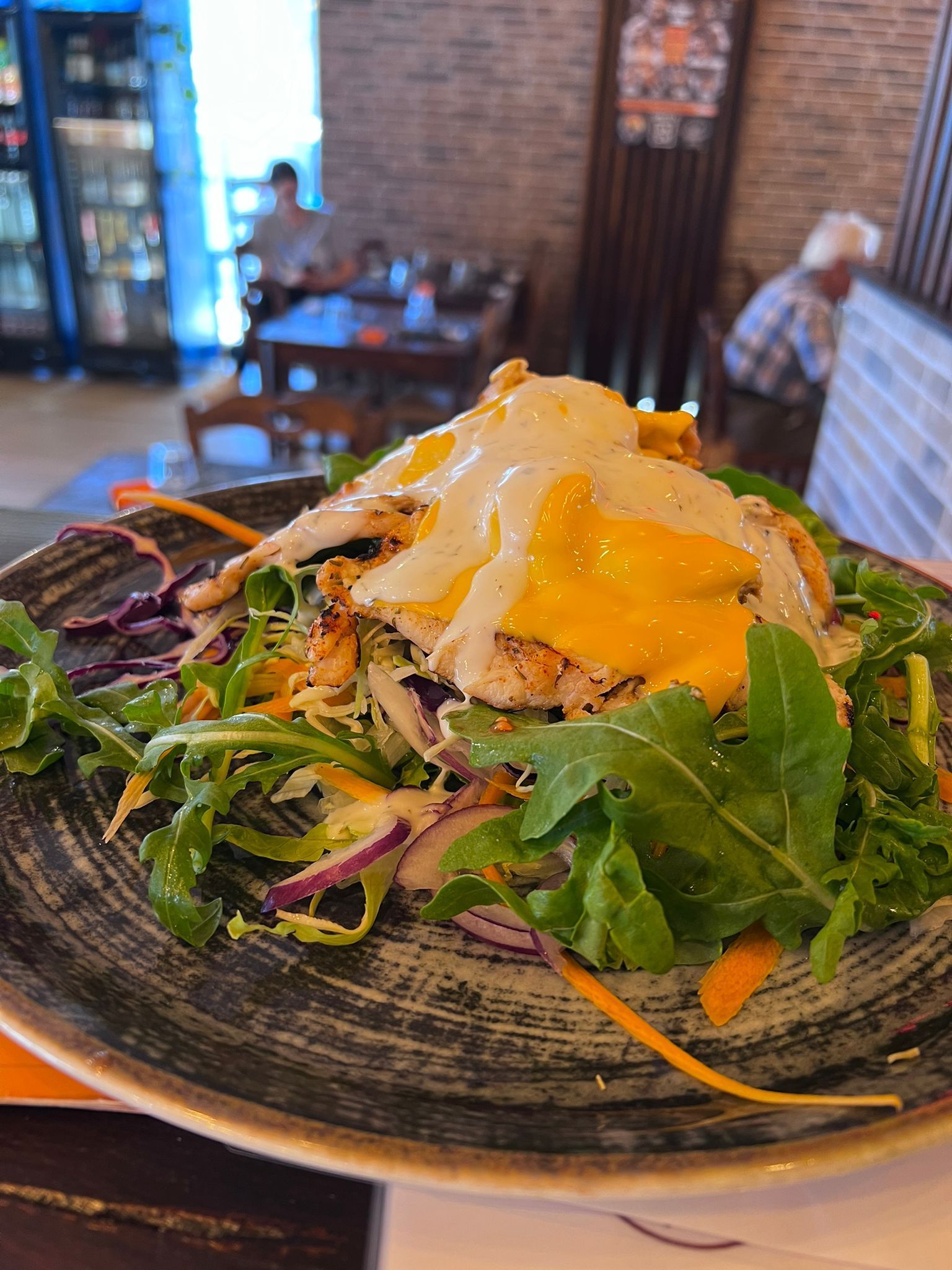 Insalata con verdure verdi, verdure tritate e condimento fritto, condita con salsa cremosa, servita su un piatto punteggiato.