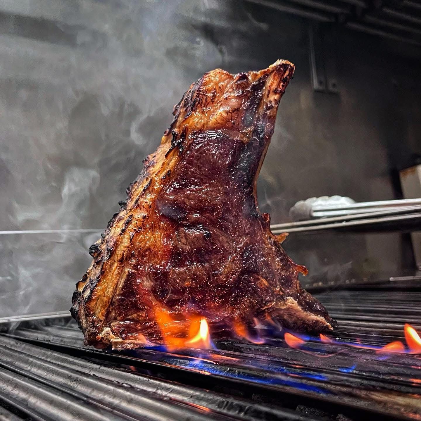 Arrosto di costata cotto su una griglia con fiamme. La carne è dorata e affumicata.