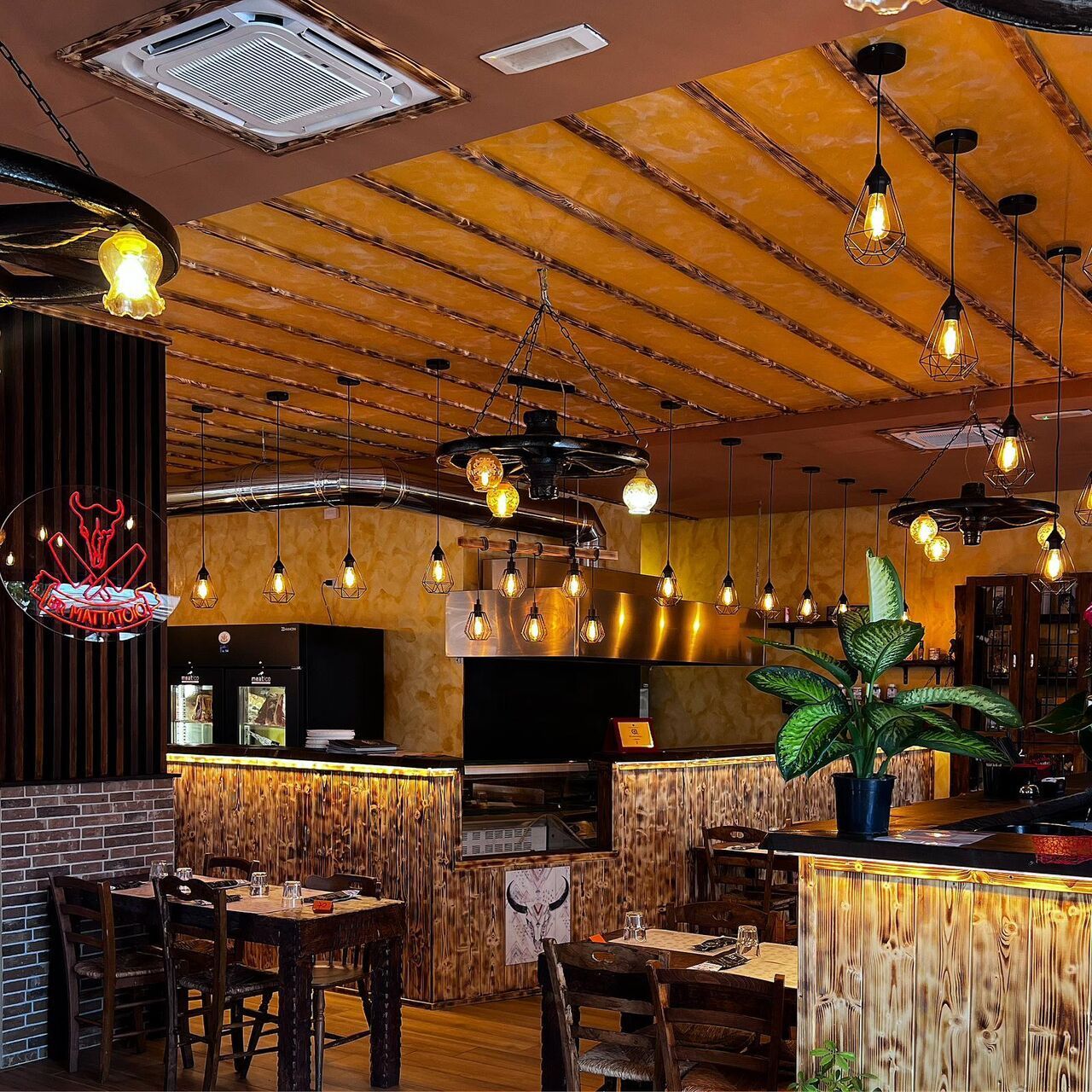 Interno del ristorante con dettagli in legno, luci soffuse e lampadine appese.