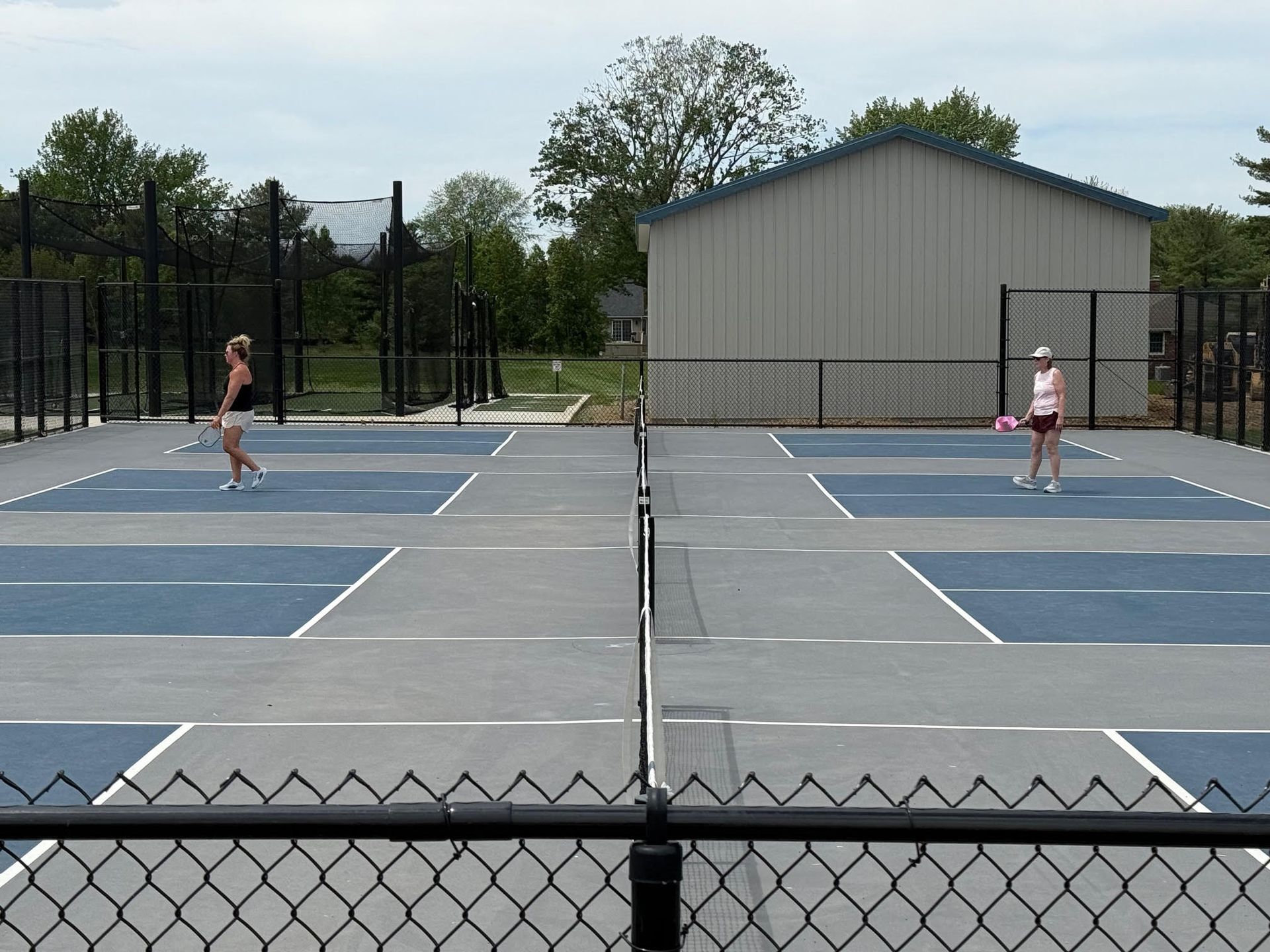 Pickleball net on a blue court; white posts, black mesh, and a blue surface.
