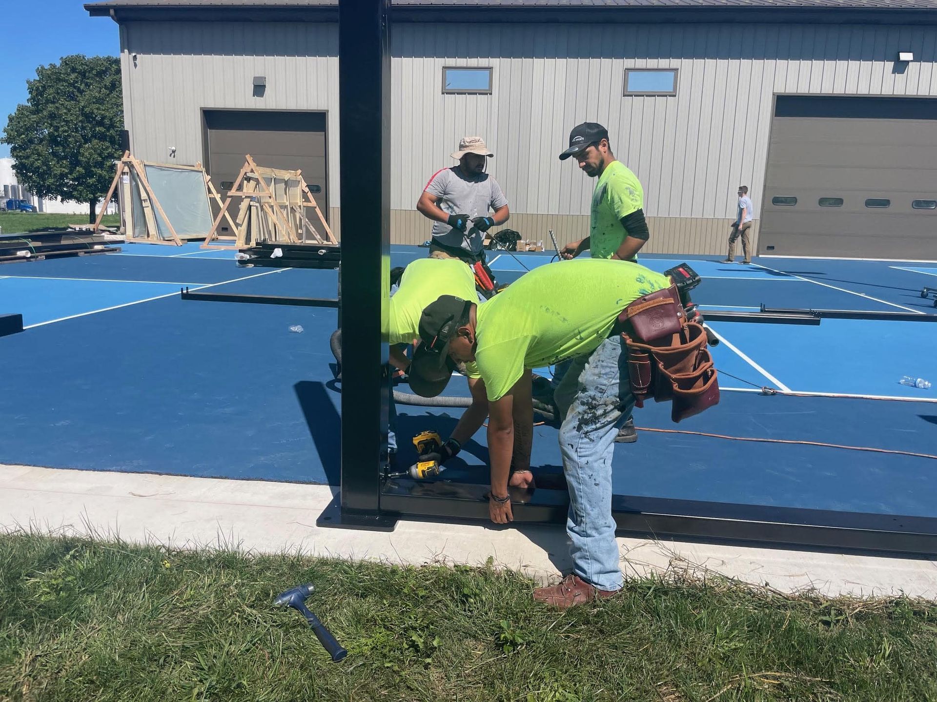 Pickleball courts with green and blue surfaces, net in the center, outdoors.