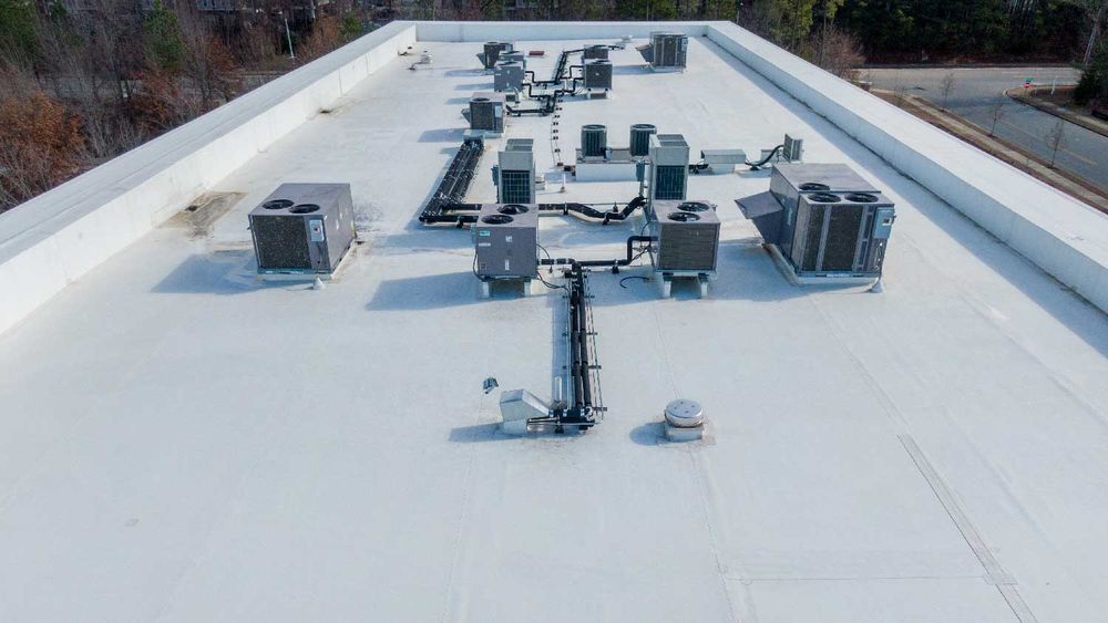 A white flat commercial roof with multiple HVAC units and equipment.