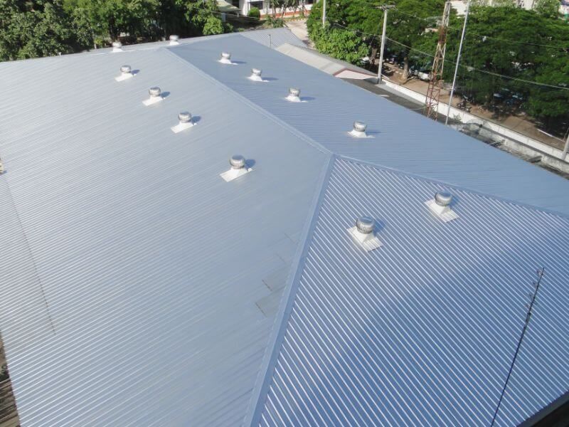 Metal roof of a building with several round ventilation fans.