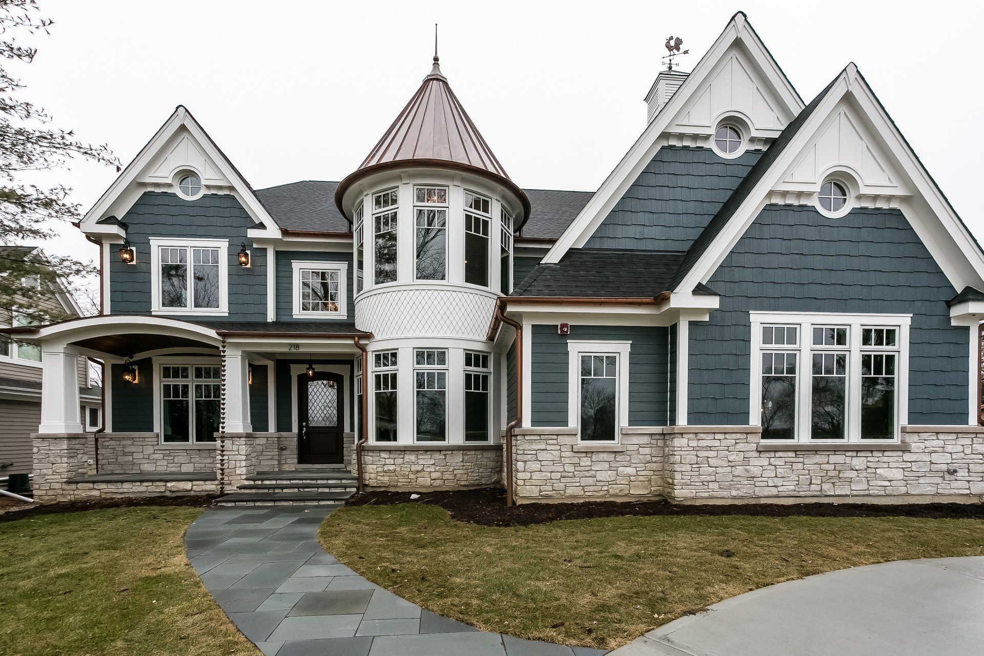 A large blue and white house with a copper roof